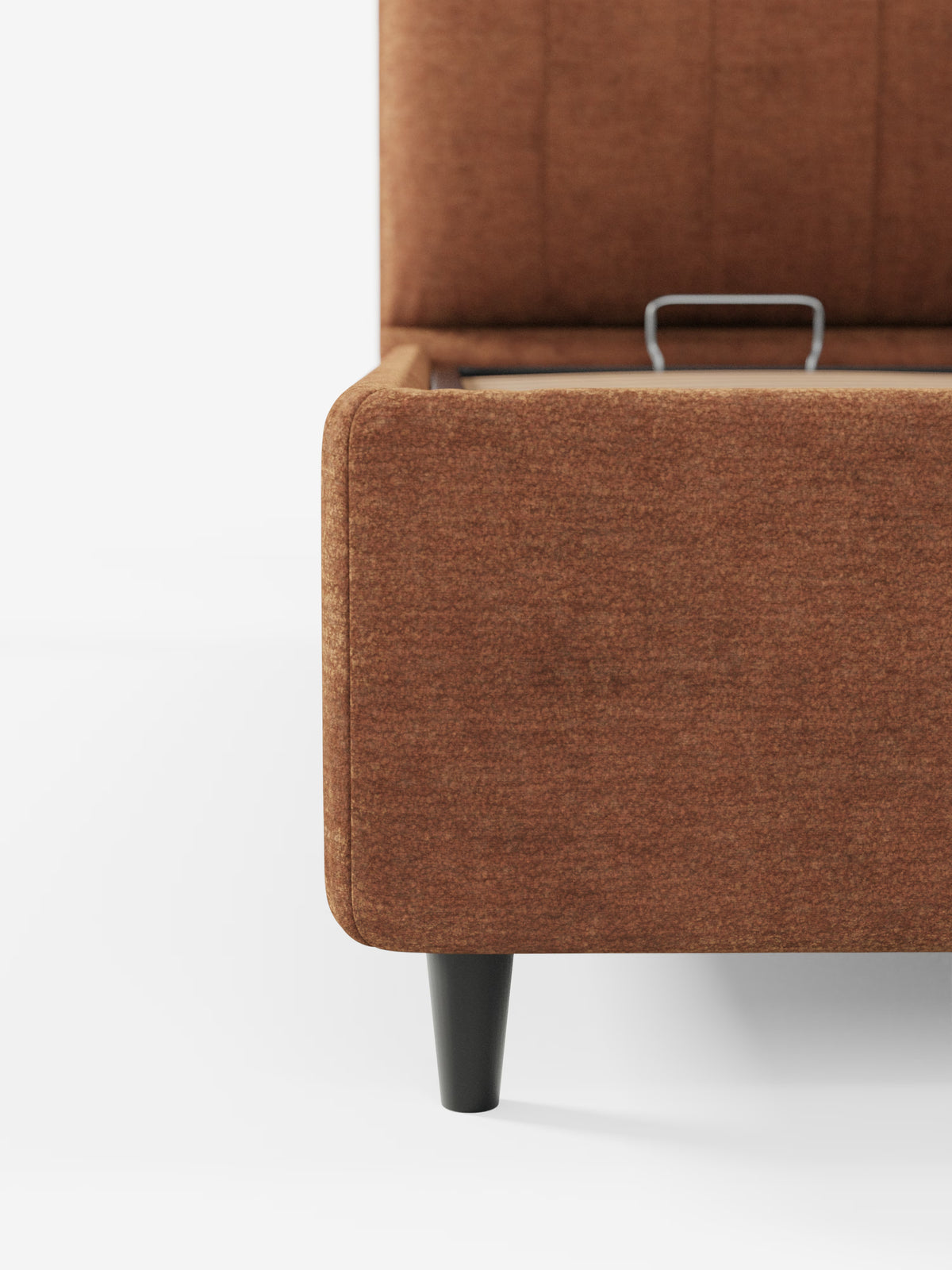 Primo piano di un letto imbottito ONYX di Letti.store, che mette in risalto il tessuto marrone testurizzato con certificazione Oeko-Tex®, una gamba affusolata nera e un vano contenitore parzialmente aperto dotato di un’elegante maniglia argentata. Lo sfondo bianco a tinta unita sottolinea il design pulito e moderno di questo elegante letto contenitore con testiera verticale.