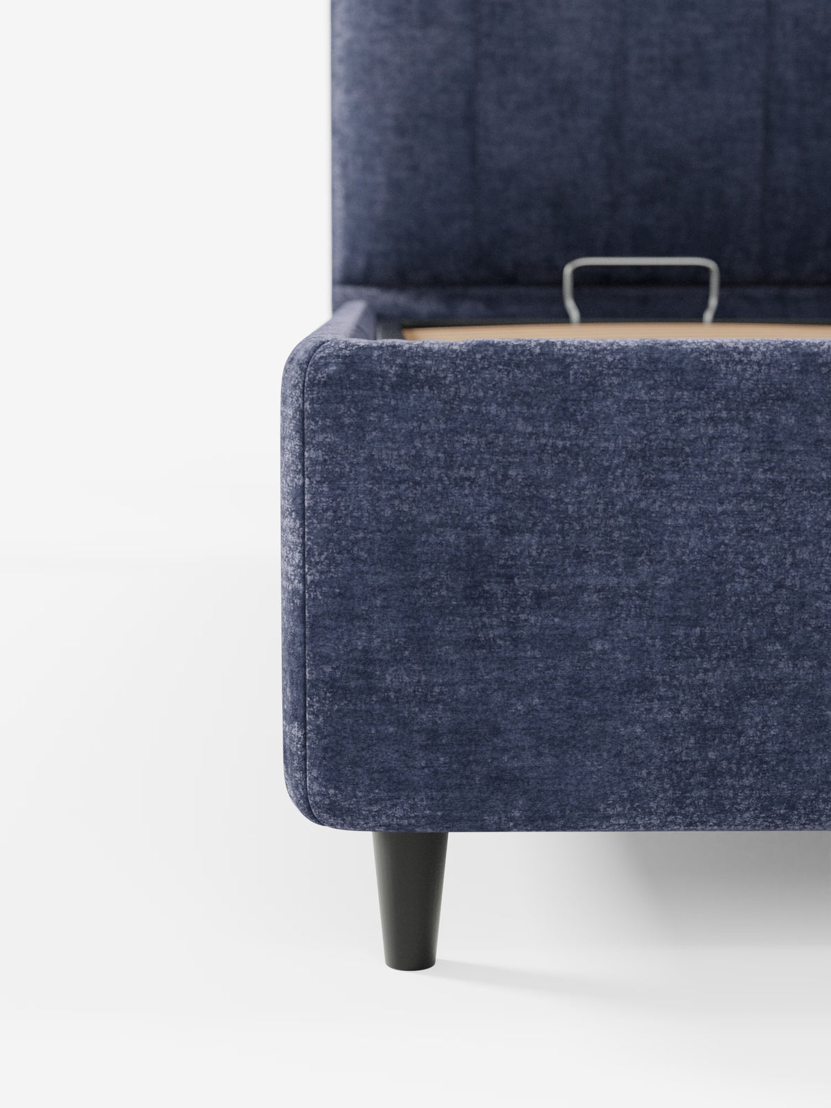 Primo piano dell'angolo del letto imbottito ONYX con contenitore e testiera verticale in tessuto certificato Oeko-Tex® di Letti.store, caratterizzato da rivestimento blu, gambe affusolate in legno nero e un vano contenitore parzialmente aperto ai piedi del letto, su sfondo bianco.