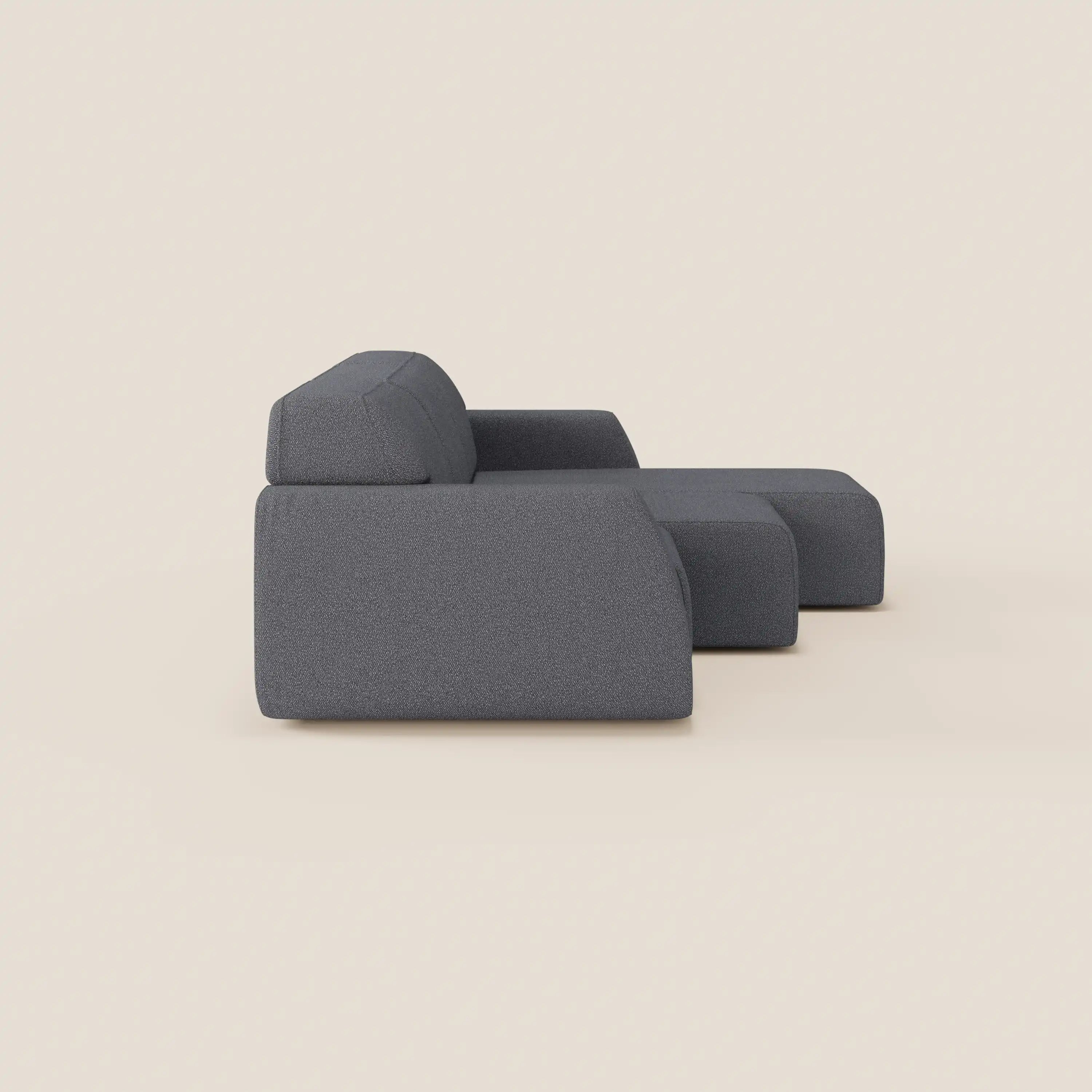 Il divano angolare Orbit con penisola reversibile e tutte le sedute allungabili in tessuto smacchiabile T33 è presentato di lato su uno sfondo beige chiaro, con linee pulite, braccioli bassi e una chaise lounge squadrata.
