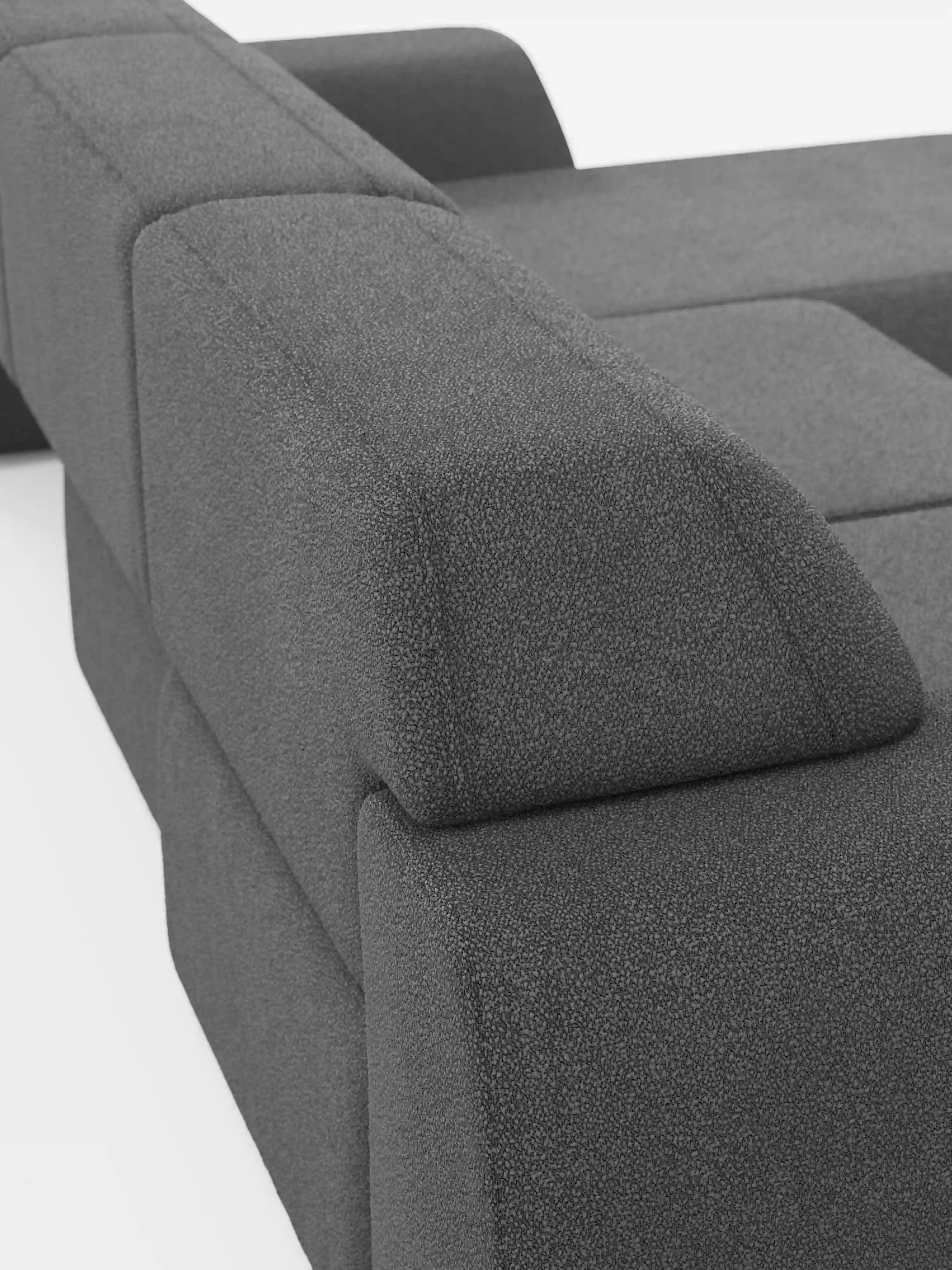 Primo piano del divano angolare Orbit con penisola reversibile e tutte le sedute allungabili, rivestito in tessuto smacchiabile effetto cotone T33 di Divani.Store, caratterizzato da moderni cuscini geometrici grigio scuro e ampi braccioli che risaltano sullo sfondo bianco. Le linee pulite e il design minimalista mettono in risalto il rivestimento in tessuto di alta qualità, morbido e dalla trama ricca, di questo lussuoso divano componibile.