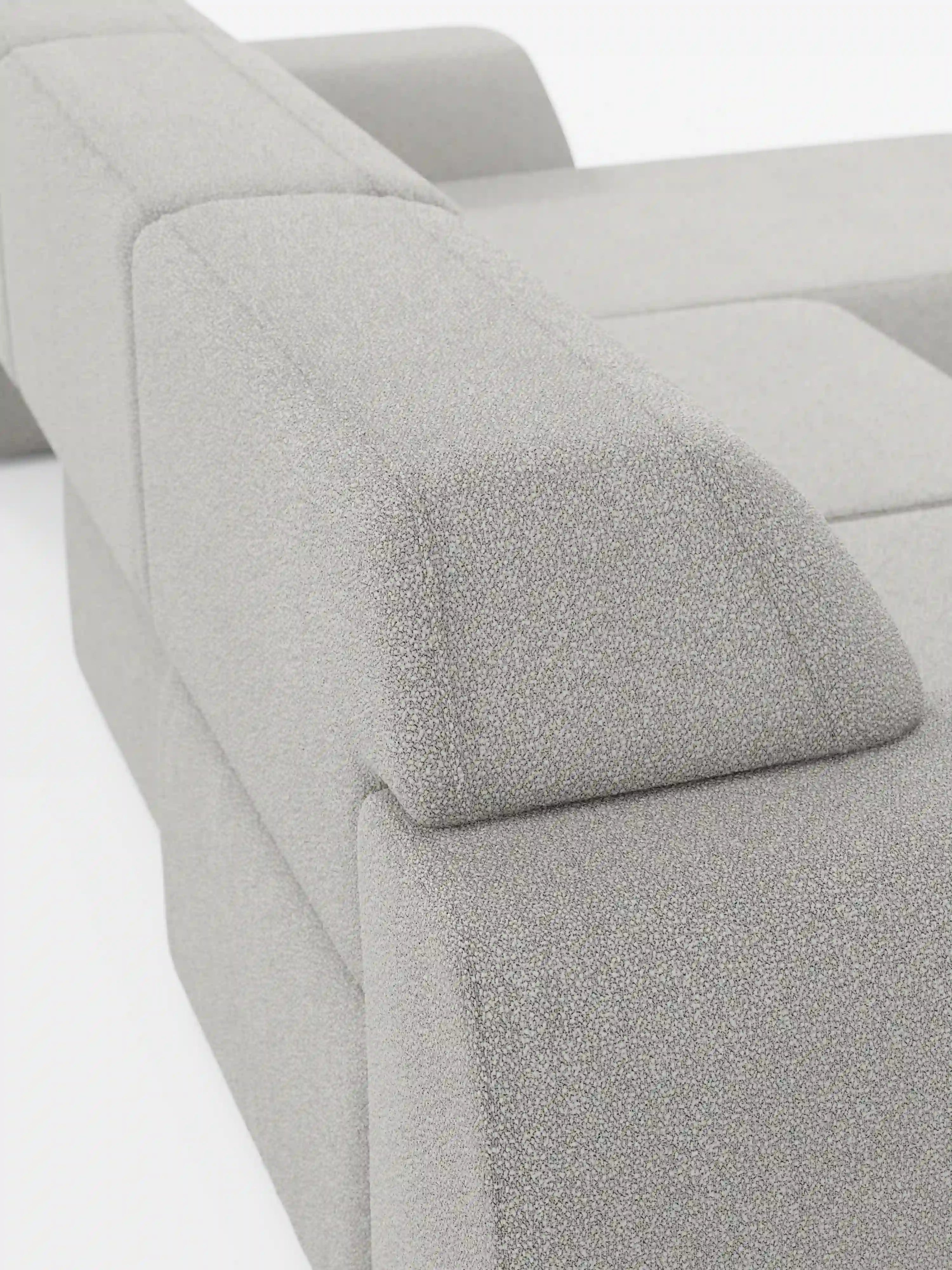 Primo piano del divano angolare Orbit con penisola reversibile e tutte le sedute allungabili in tessuto smacchiabile effetto cotone T33 di Divani.Store. L'immagine mette in risalto il bracciolo spesso e dalle forme geometriche e il rivestimento grigio chiaro con texture, sottolineando le linee pulite e spigolose e la disposizione modulare con chaise longue reversibile, tipica di questo divano contemporaneo. Lo sfondo è bianco a tinta unita.