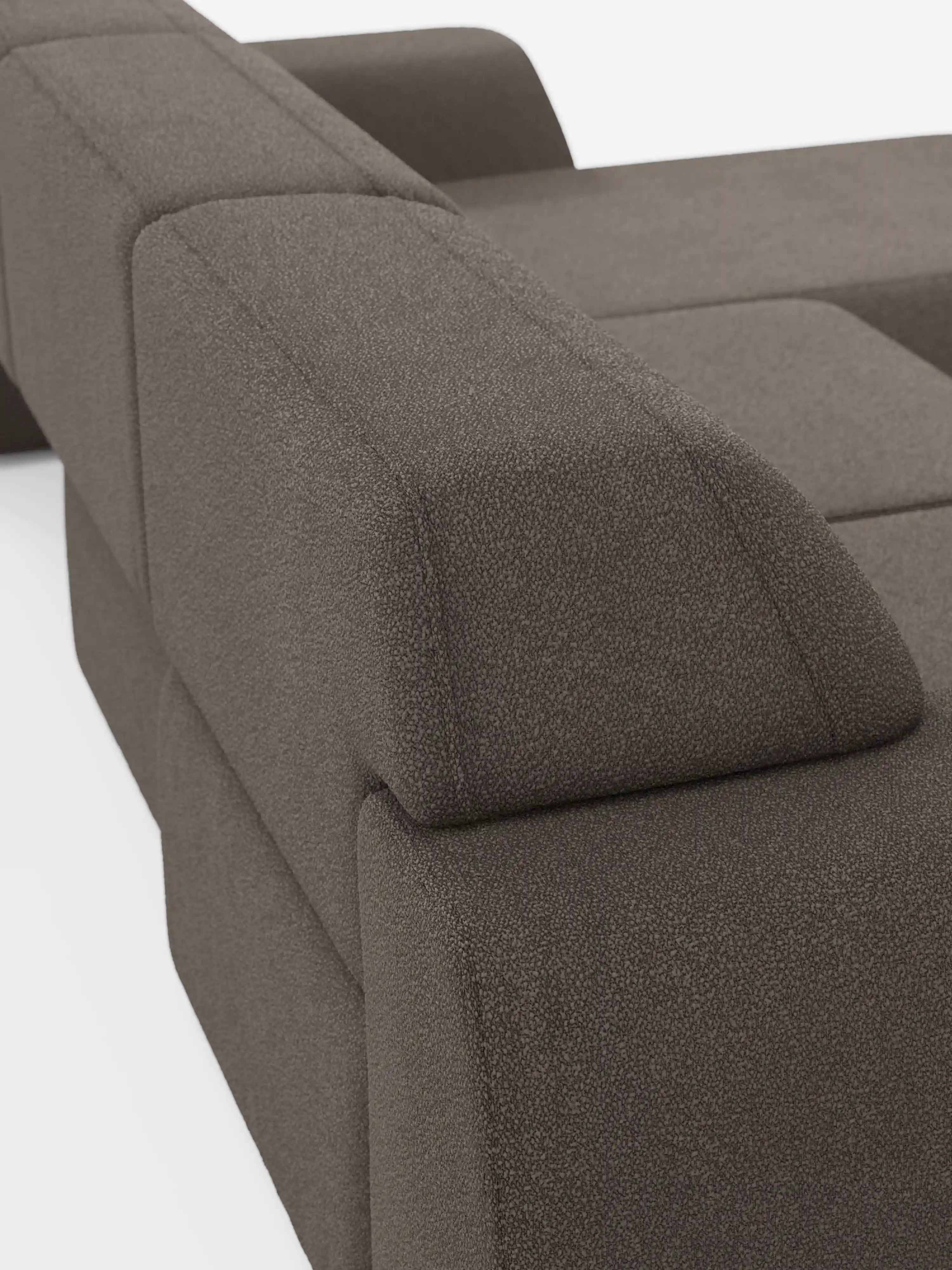 Primo piano del divano angolare Orbit con penisola reversibile e tutte le sedute allungabili di Divani.Store, rivestito in tessuto T33 effetto cotone, testurizzato e facile da pulire, in colore marrone. L’immagine mette in risalto gli ampi braccioli e lo schienale rettangolari del divano, dalle linee pulite e spigolose, su uno sfondo bianco, sottolineandone il design geometrico audace.