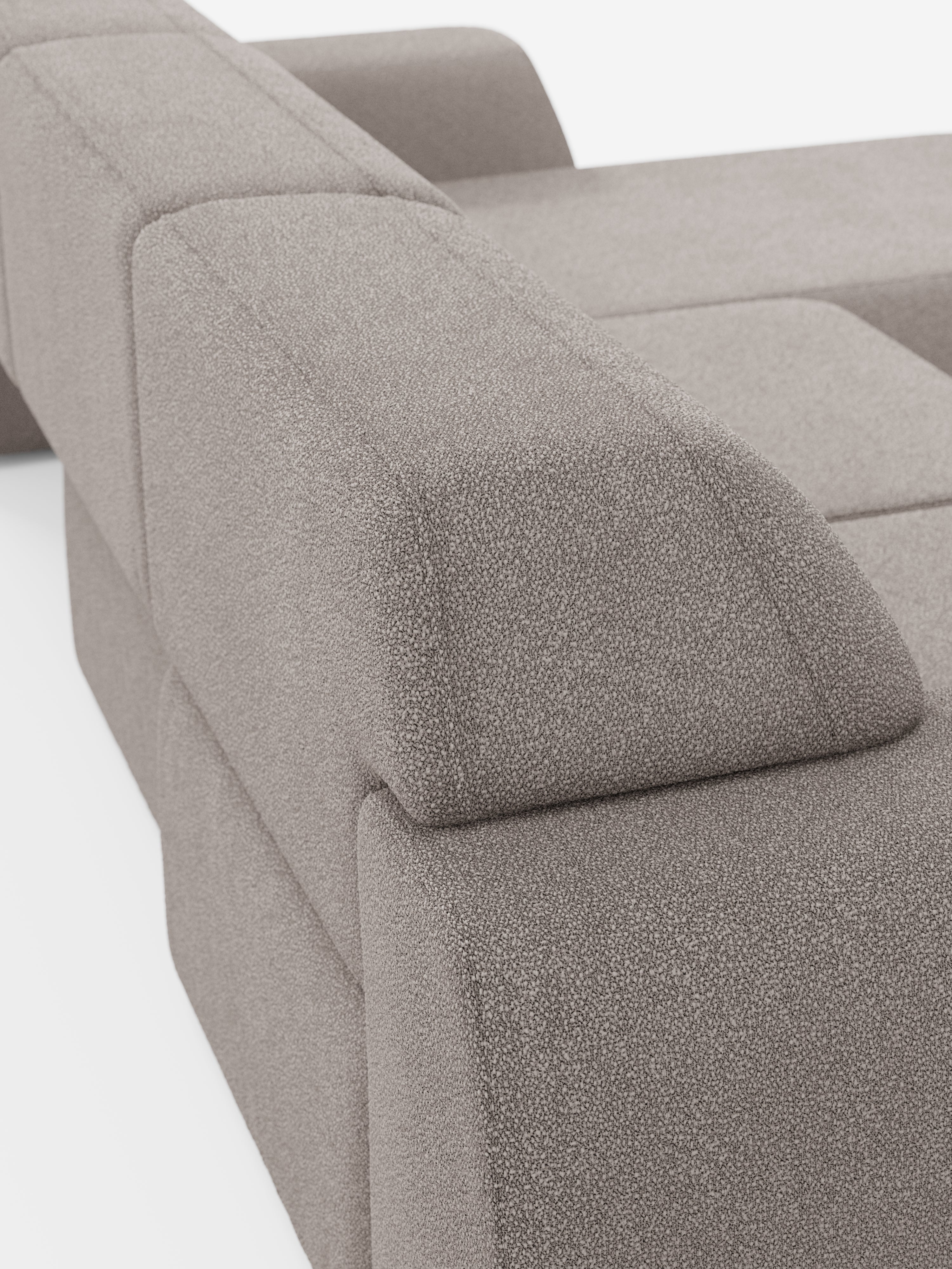 Primo piano del divano angolare Orbit con penisola reversibile e tutte le sedute allungabili di Divani.Store, rivestito in tessuto T33 effetto cotone grigio chiaro, resistente alle macchie. Questo moderno divano componibile si caratterizza per le forme geometriche a blocchi e gli ampi braccioli. L’immagine mette in risalto il bracciolo e lo schienale, sottolineando la consistenza morbida, le linee pulite e raffinate e il design contemporaneo di questo pezzo di alta gamma.