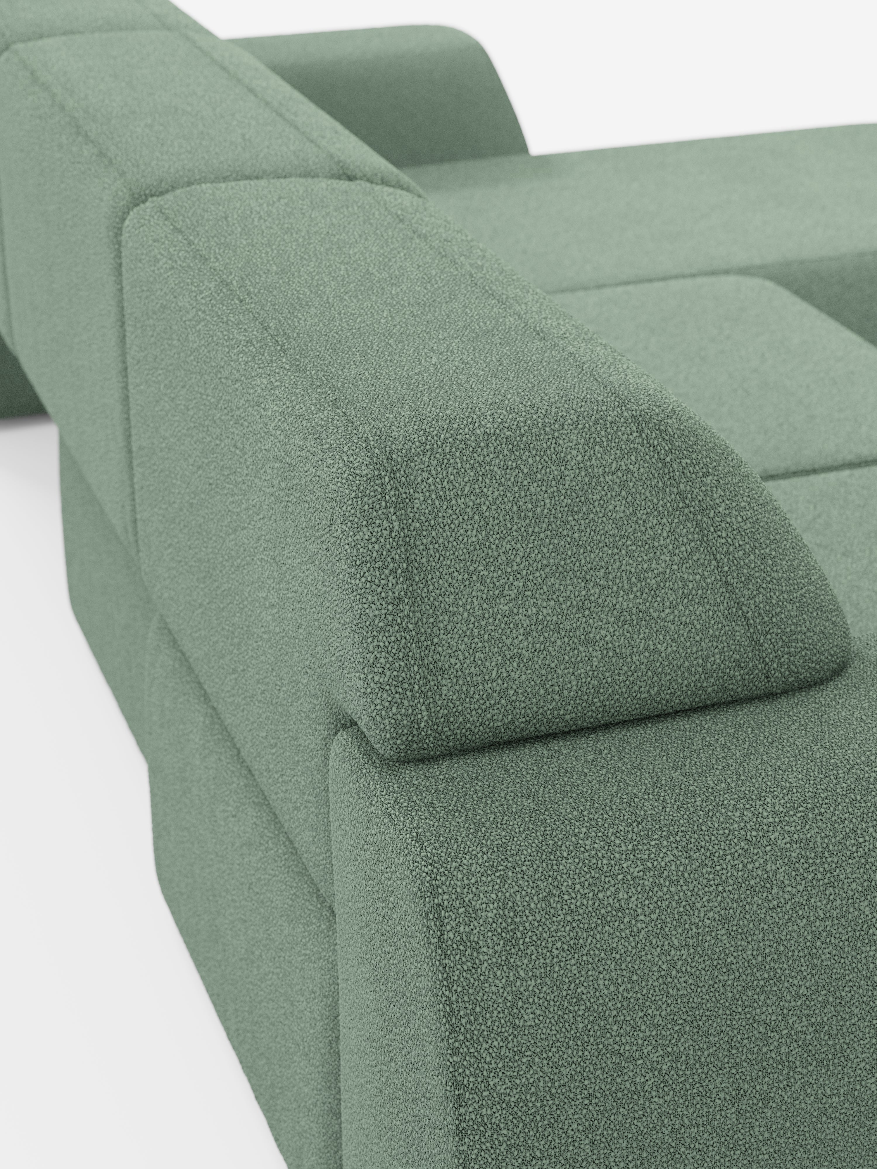 Primo piano del divano angolare Orbit con penisola reversibile e tutte le sedute allungabili in tessuto smacchiabile effetto cotone T33 di Divani.Store. L'immagine mette in risalto il design moderno con tessuto verde testurizzato effetto cotone, concentrandosi sui braccioli e sullo schienale per accentuare le linee pulite e le forme geometriche morbide e squadrate. Su uno sfondo bianco a tinta unita, questo elegante divano di alta gamma si presenta in tutto il suo raffinato dettaglio.