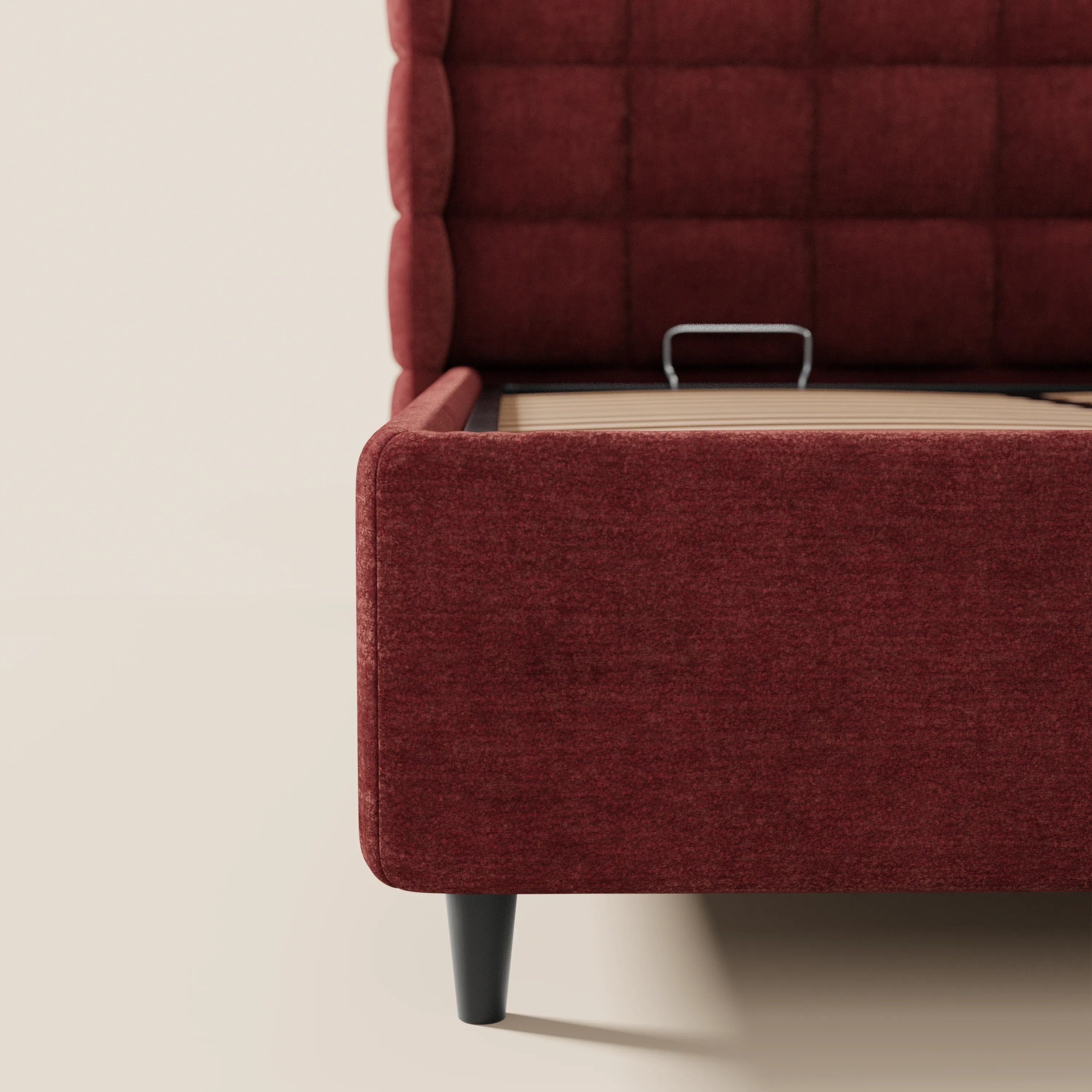 Primo piano del letto imbottito RAGNAR di Letti.store, realizzato in tessuto rosso intenso certificato Oeko-Tex®, caratterizzato da una testiera avvolgente capitonné con motivo a griglia trapuntata, gambe affusolate nere a vista e base con contenitore.