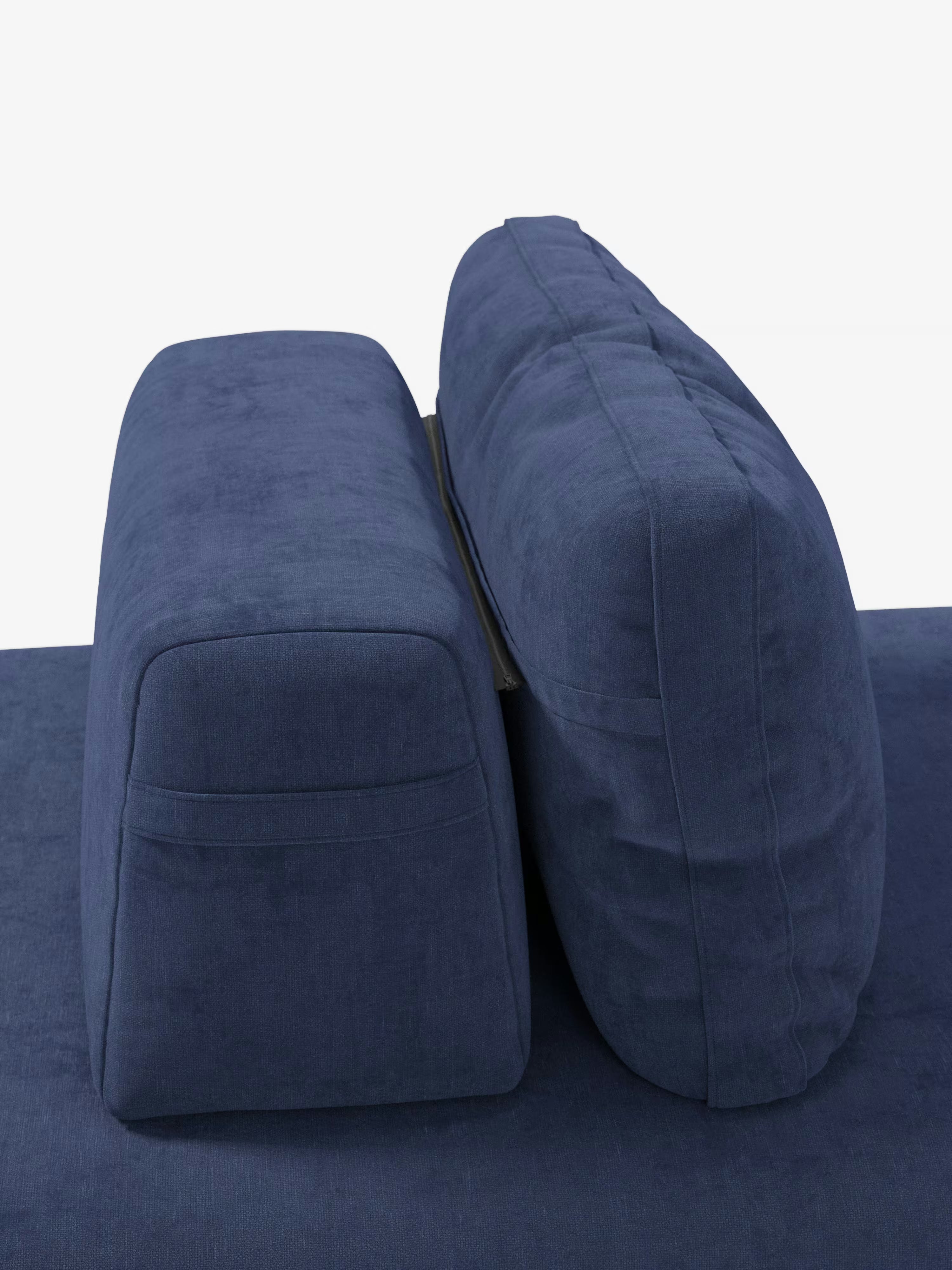 Due cuscini imbottiti blu della linea “Rift” – divano letto matrimoniale a 2 e 3 posti con schienali mobili di Divani.Store – sono disposti in posizione verticale uno contro l’altro su una superficie blu abbinata, evocando le linee eleganti del design italiano contemporaneo. Il cuscino a sinistra è rettangolare con bordi ben definiti, mentre quello a destra è più alto, arrotondato e leggermente inclinato all’indietro. Lo sfondo è bianco a tinta unita.