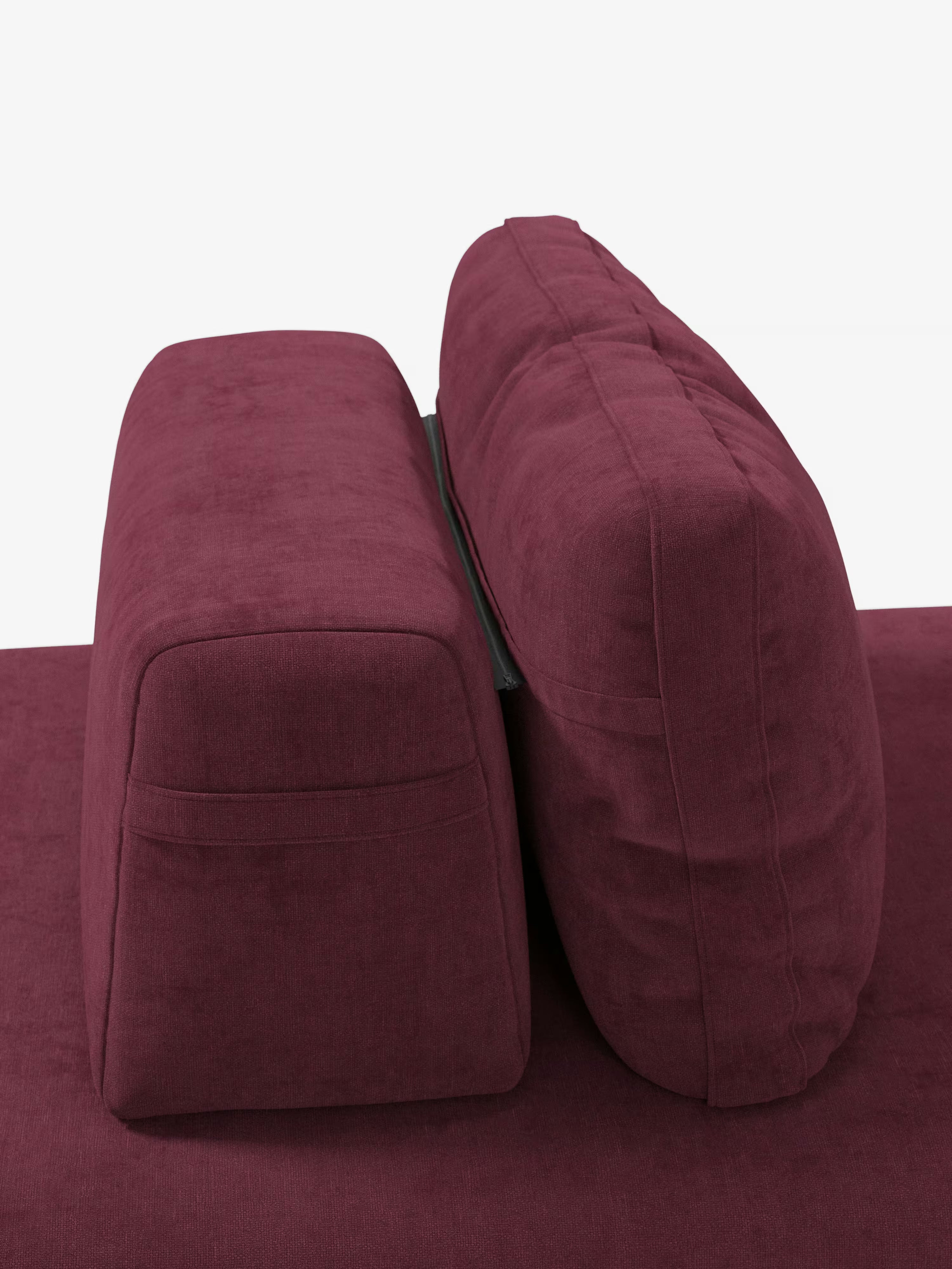 Un primo piano del divano letto matrimoniale Rift a 2 e 3 posti con schienali mobili di Divani.Store mostra la vista laterale di un bracciolo e di un cuscino dello schienale. Il tessuto T31 color bordeaux, antimacchia, appare morbido e vellutato, mentre i cuscini spessi e il materasso in memory foam alto 24 cm offrono un comfort eccezionale. Uno sfondo bianco a tinta unita mette in risalto i dettagli di questo divano letto di design.