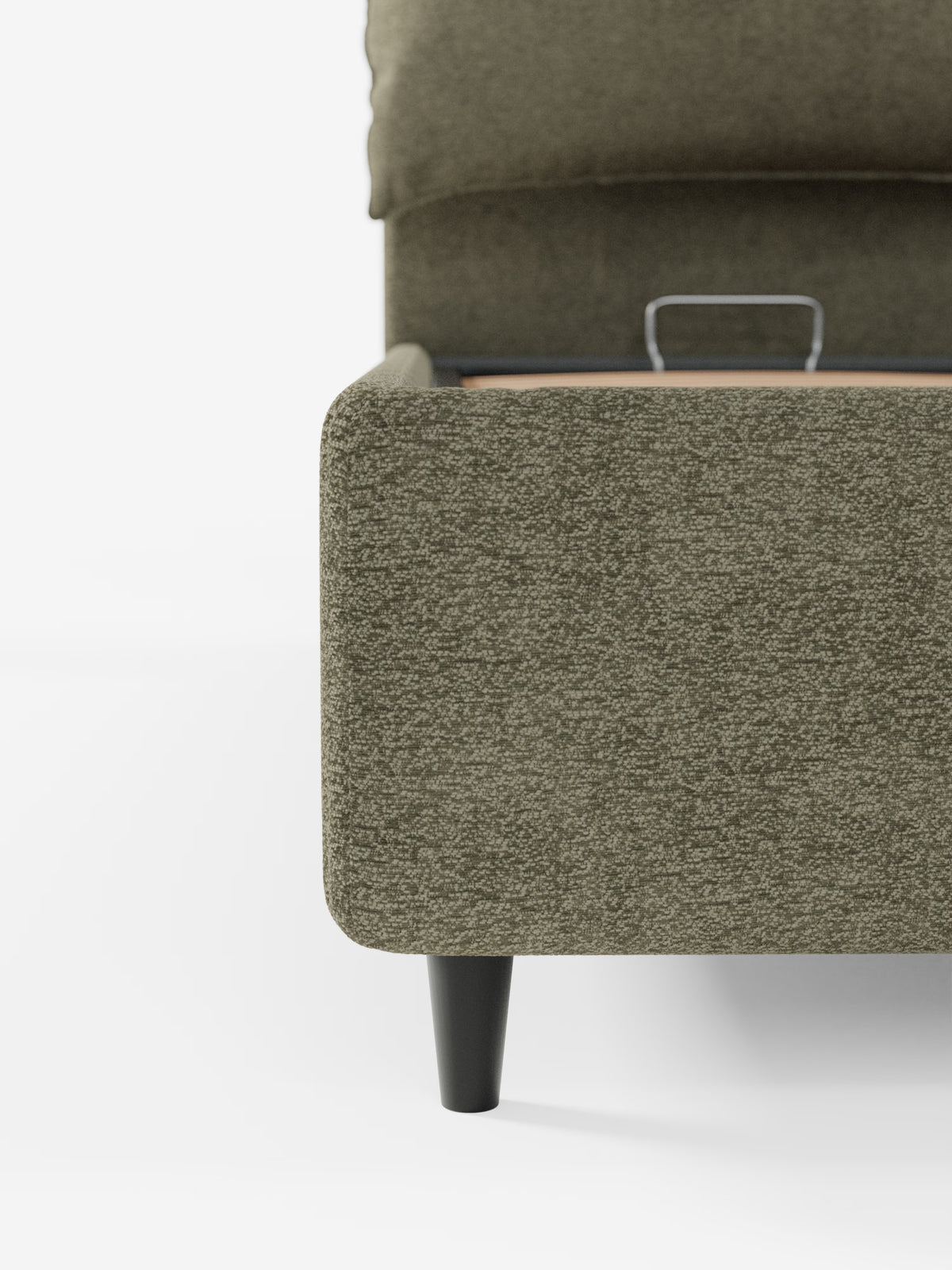 Primo piano dell’angolo del letto imbottito ZAYRON con vano contenitore e morbidi cuscini regolabili di Letti.store, qui raffigurato in tessuto verde oliva certificato Oeko-Tex®. L’immagine mette in risalto il rivestimento testurizzato del letto e una robusta gamba in legno nero, con un accenno di una doga metallica all’interno del telaio. È visibile solo un lato, su uno sfondo bianco a tinta unita.