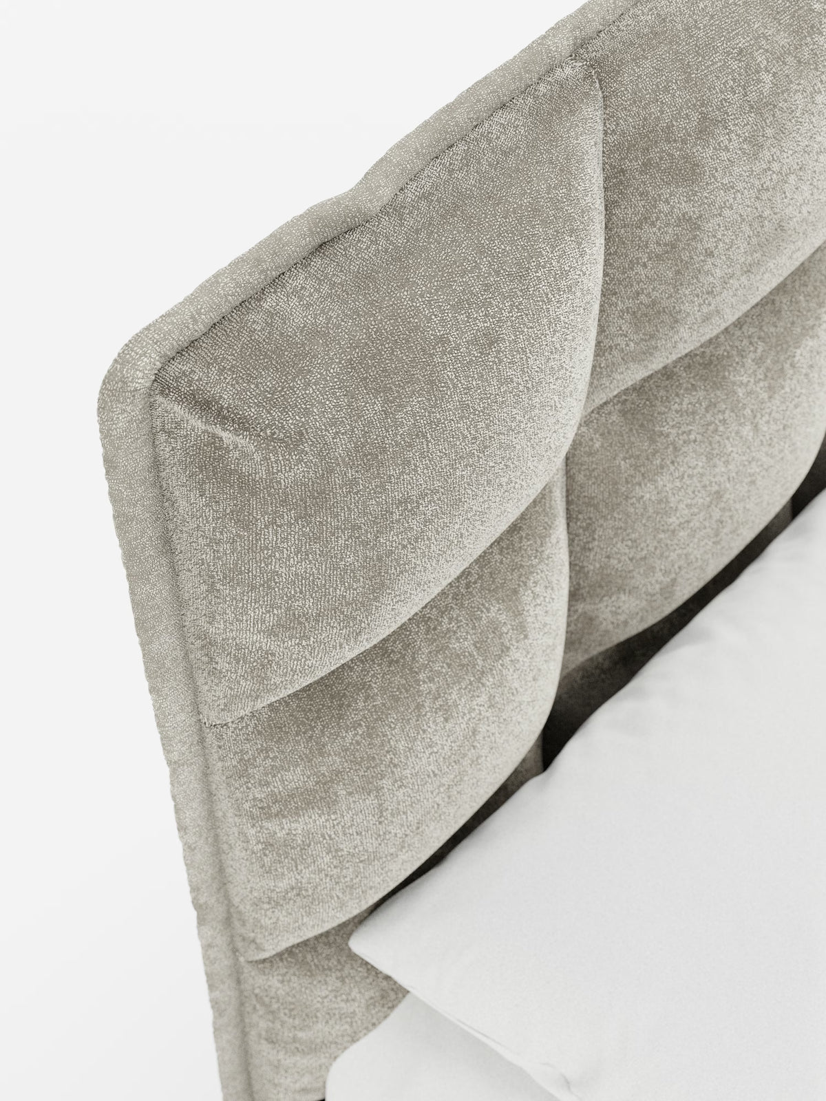 Primo piano del letto imbottito AURO con contenitore e testiera alta capitonné in ciniglia Oeko-Tex® di Letti.store. La raffinata testiera alta capitonné è rivestita in ciniglia grigio chiaro (rivestimento in tessuto ciniglia), che ne esalta l’aspetto morbido e lussuoso grazie ai raffinati dettagli capitonné. Un cuscino poggia contro l’elegante testiera su un letto bianco, mentre lo sfondo bianco e pulito mette in risalto la sua sofisticata lavorazione artigianale.