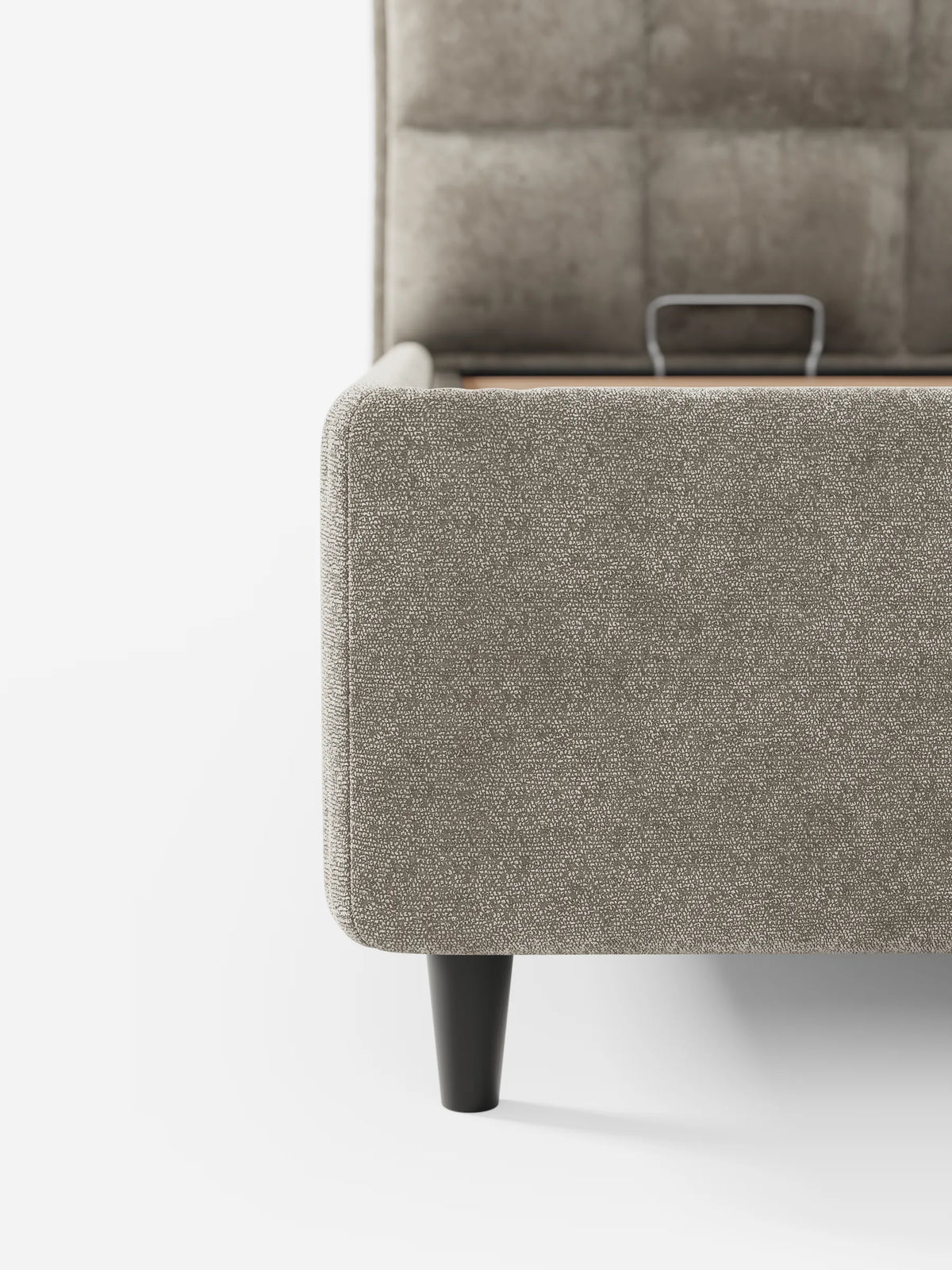 Un primo piano di un letto imbottito AURO con vano contenitore e testiera capitonné alta in ciniglia Oeko-Tex® in tessuto taupe testurizzato, con gambe in legno scuro, che mostra la testiera quadrata capitonné e il vano contenitore sollevato.