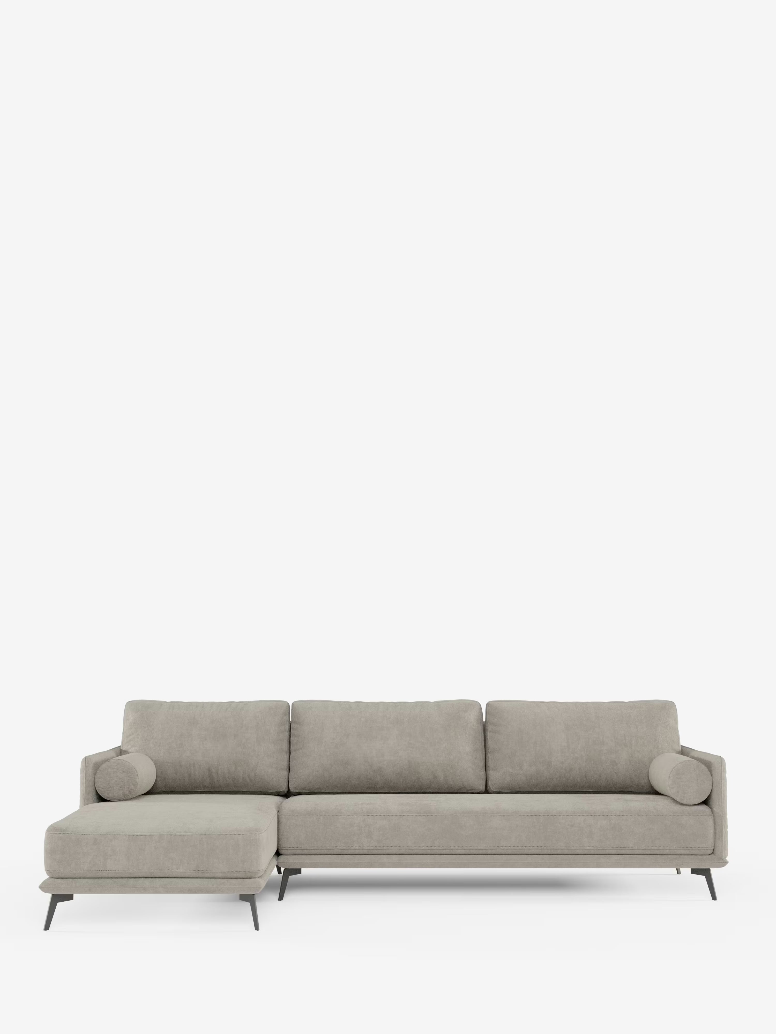 Il divano moderno angolare con penisola Basalto di Divani.Store presenta un rivestimento in tessuto T31 grigio chiaro e resistente alle macchie, con tre cuscini di seduta, tre cuscini di schienale, due cuscini cilindrici, sottili gambe in metallo nero e una chaise longue posizionata sul lato sinistro. Il divano è ripreso su uno sfondo bianco a tinta unita.