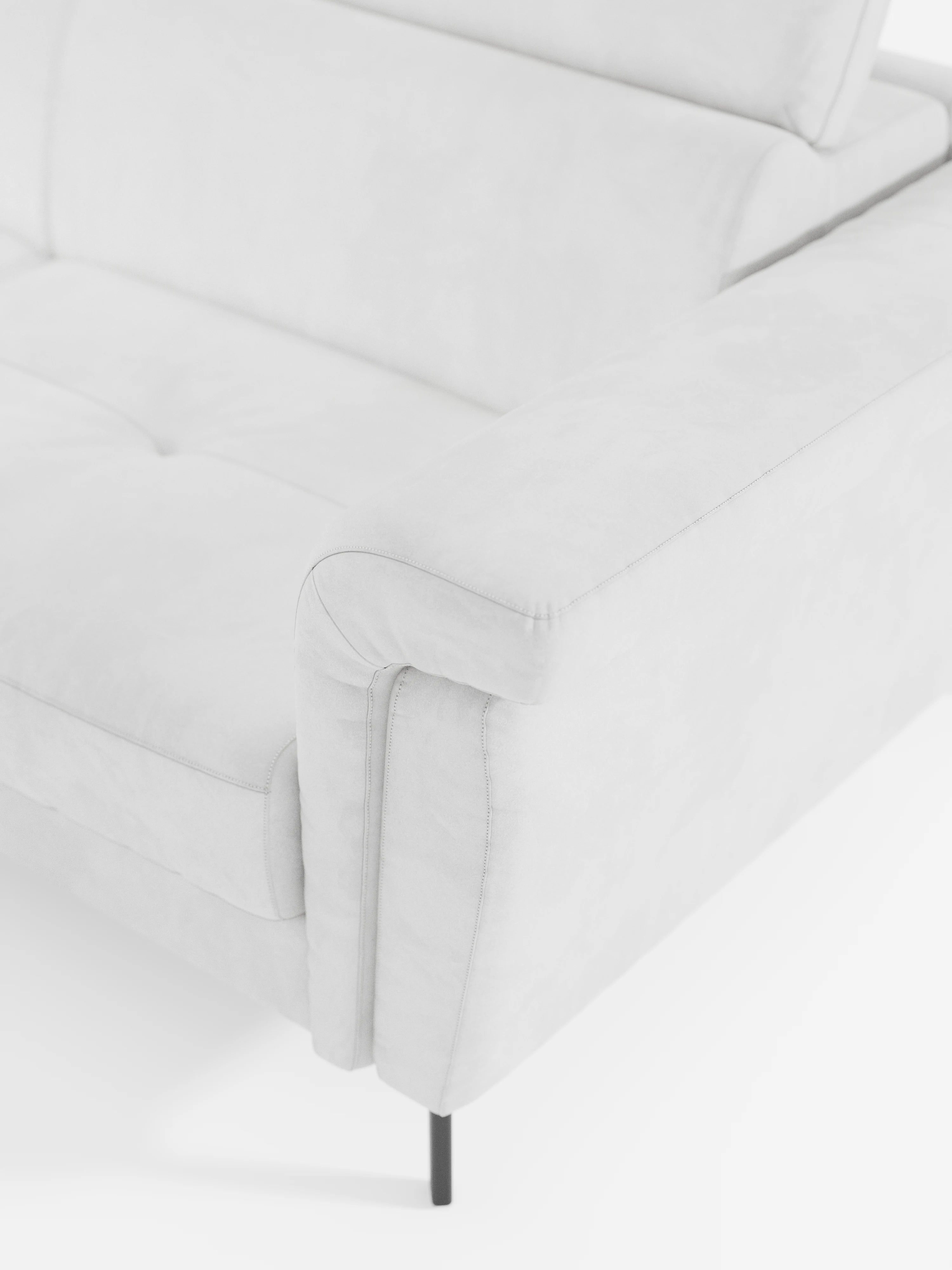 Un primo piano del divano letto angolare Capri con poggiatesta reclinabili e materasso ad alte prestazioni in tessuto vellutino smacchiabile T30 di Divani.Store, che mette in risalto il bracciolo, il cuscino di seduta e lo schienale. Il divano è rivestito in un morbido tessuto vellutato antimacchia e presenta sottili gambe in metallo nero. L’immagine mette in risalto le linee moderne e minimaliste del divano angolare, un esempio ideale di design moderno per interni contemporanei.