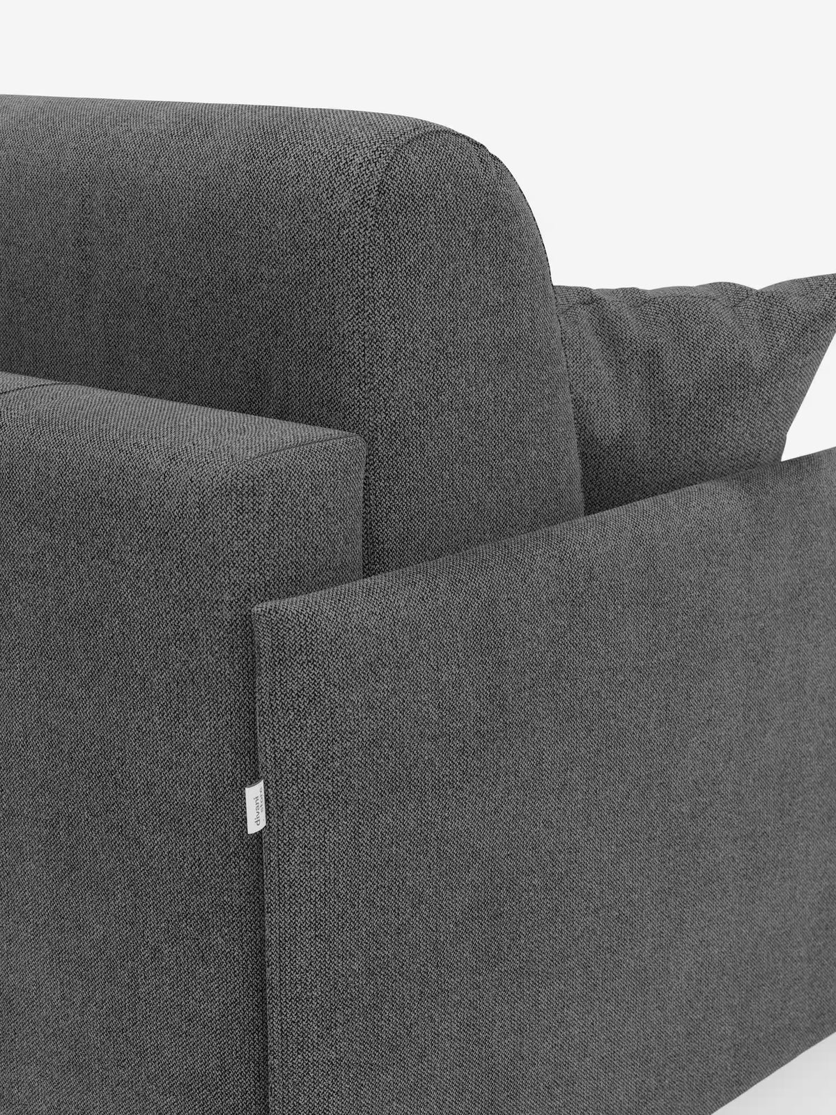 Primo piano del divano letto matrimoniale sfoderabile Evans di Divani.Store, caratterizzato da un moderno tessuto strutturato grigio scuro con schienale, braccioli e cuscino coordinato a vista. Una piccola etichetta bianca è apposta vicino al bordo inferiore. Questo design compatto, dotato di un pratico vano porta guanciali in tessuto smacchiabile T23, è perfetto per ottimizzare lo spazio senza rinunciare allo stile. Lo sfondo è bianco a tinta unita.