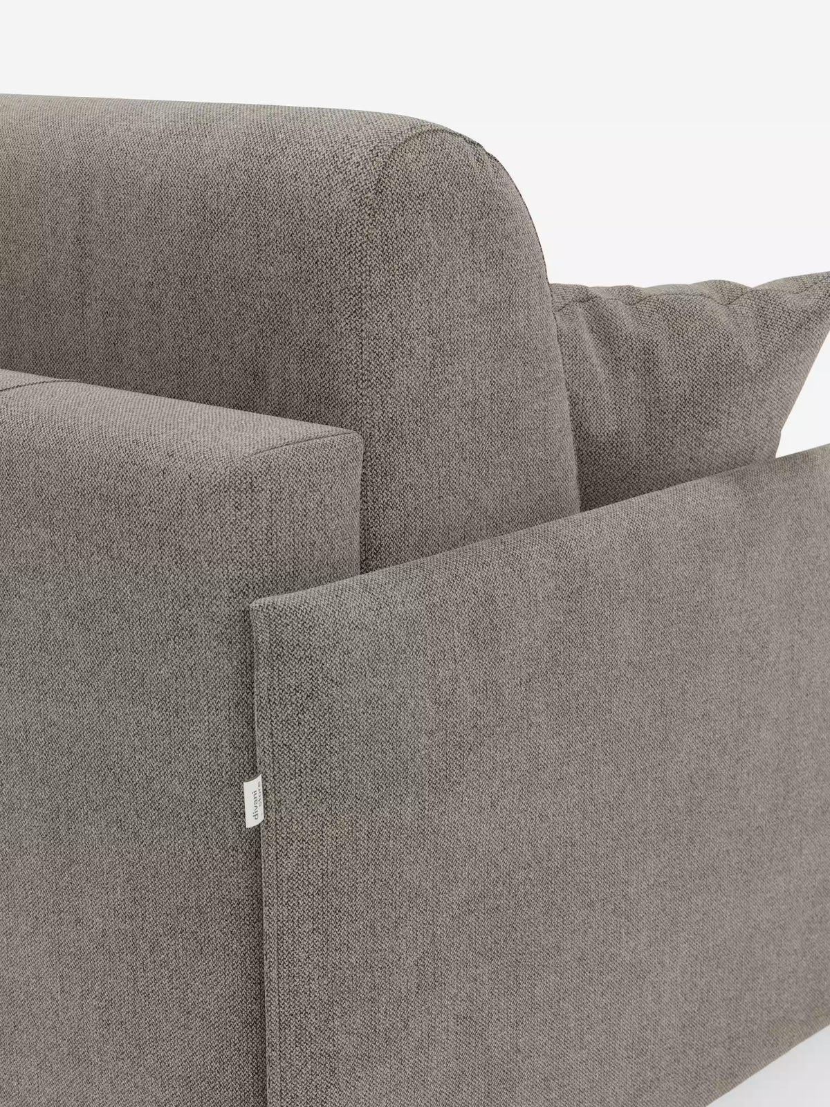 Primo piano dell'angolo del divano letto matrimoniale sfoderabile Evans di Divani.Store, rivestito in tessuto grigio T23 resistente alle macchie. L'immagine mette in risalto il bracciolo, lo schienale e il cuscino, con una piccola etichetta in tessuto sul lato. Il design è minimalista e si staglia su uno sfondo bianco a tinta unita.