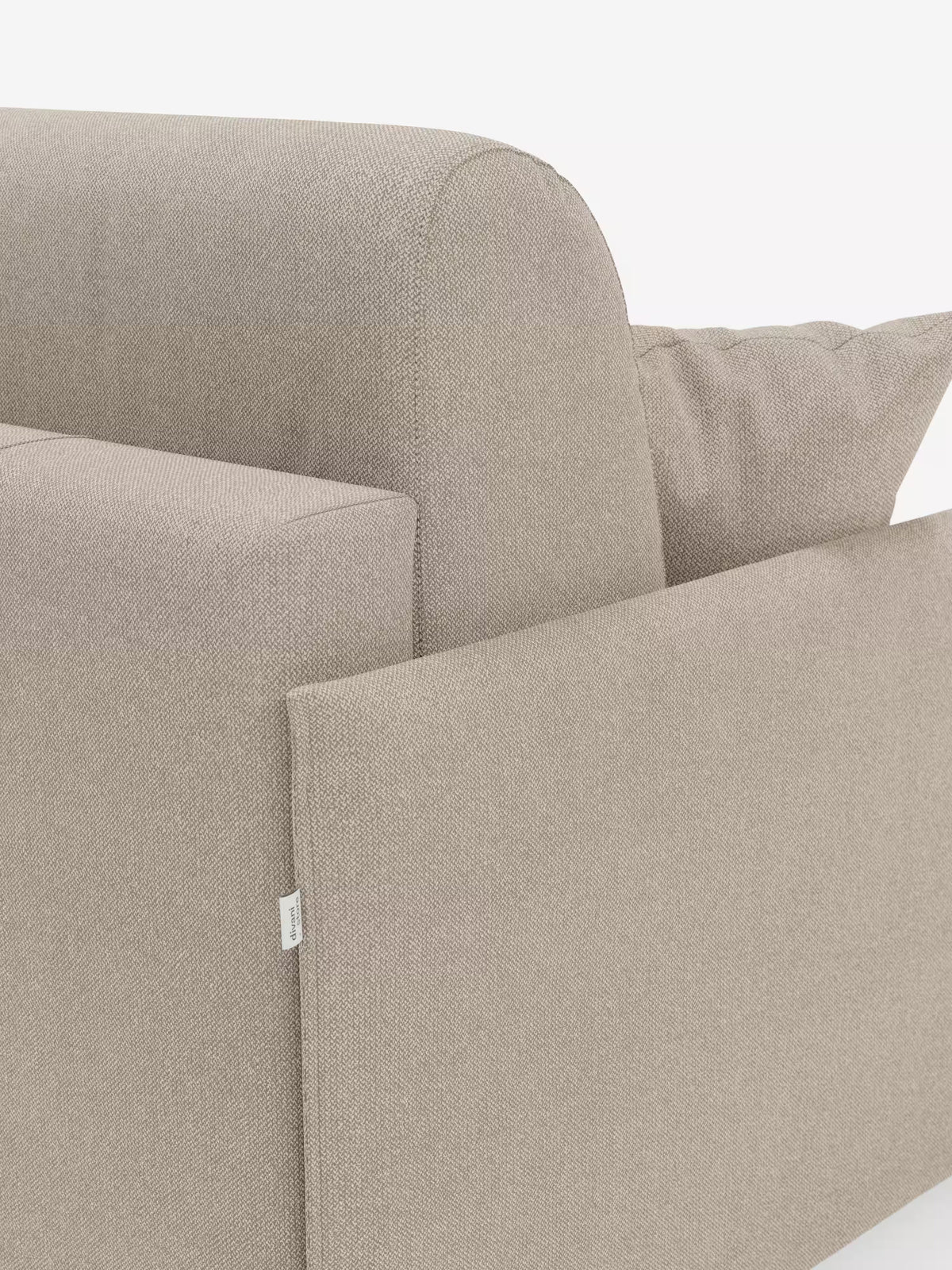 Primo piano del divano letto matrimoniale sfoderabile Evans di Divani.Store, rivestito in tessuto T23 beige chiaro antimacchia. Il design compatto presenta un bracciolo rettangolare, un morbido cuscino coordinato e una piccola etichetta bianca sul lato. La trama visibile del tessuto ne sottolinea la qualità artigianale e include un pratico vano porta-cuscini. Lo sfondo è bianco a tinta unita.