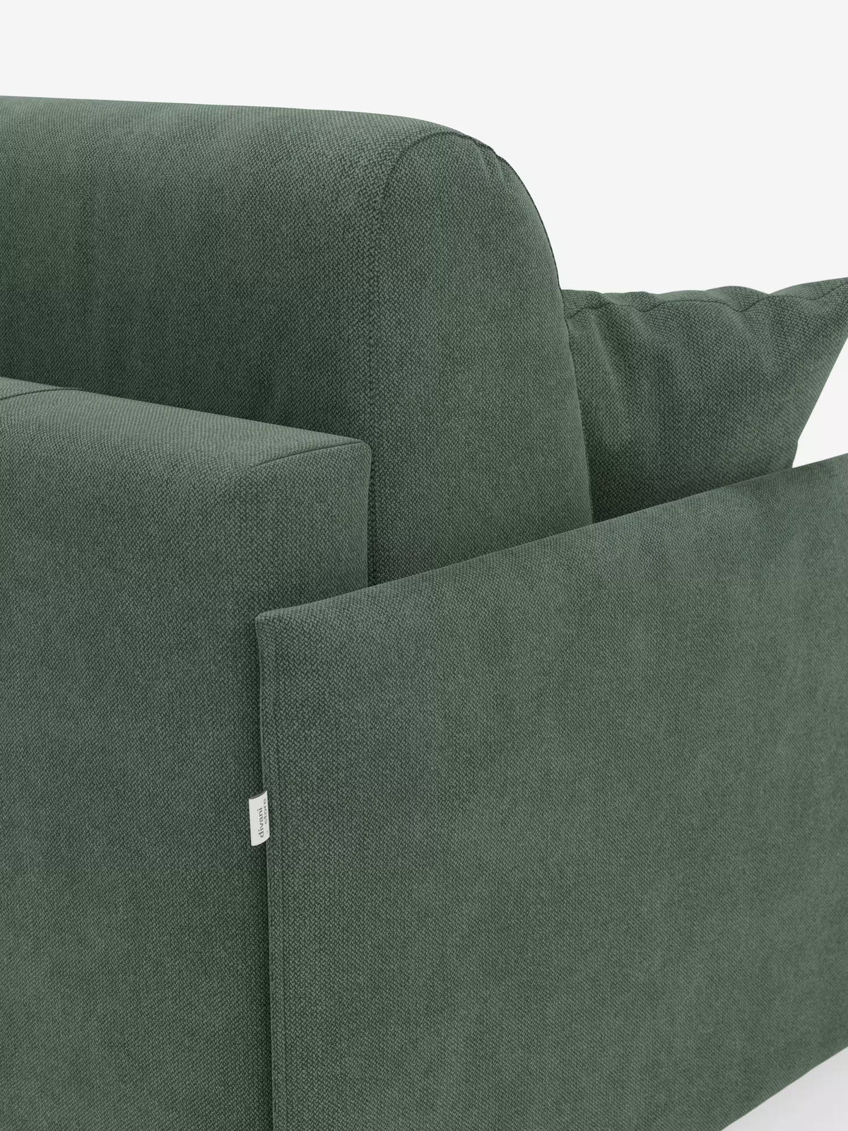 Primo piano del divano letto matrimoniale sfoderabile Evans di Divani.Store, rivestito in tessuto T23 verde antimacchia con una delicata trama in rilievo. Il design compatto comprende un bracciolo rettangolare, un morbido cuscino dello schienale e un cuscino decorativo abbinato. Sulla cucitura esterna del bracciolo è visibile una piccola etichetta bianca. Con il suo pratico vano portaoggetti per i cuscini e lo stile elegante e contemporaneo, questo divano letto è un complemento d’arredo ideale per