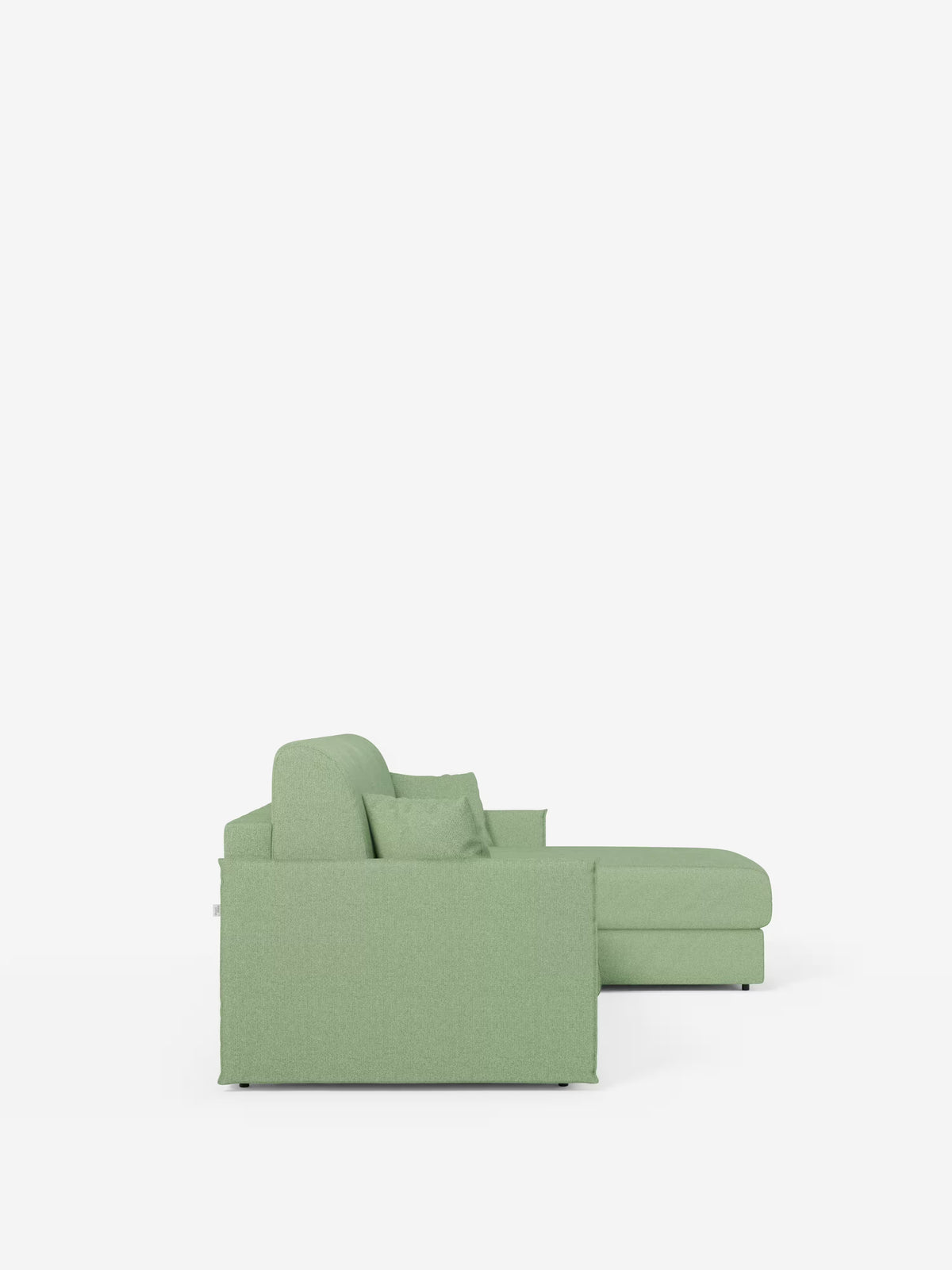 Il divano letto angolare con penisola contenitore Evans di Divani.Store è un divano componibile a forma di L di colore verde chiaro, ripreso di profilo su uno sfondo bianco a tinta unita. Questo modello compatto, realizzato in tessuto T23 antimacchia, presenta linee pulite, uno schienale basso, un unico cuscino di seduta e una chaise longue con penisola contenitore sul lato destro. Un cuscino decorativo con rivestimento coordinato completa questo elemento d'arredo elegante e funzionale.