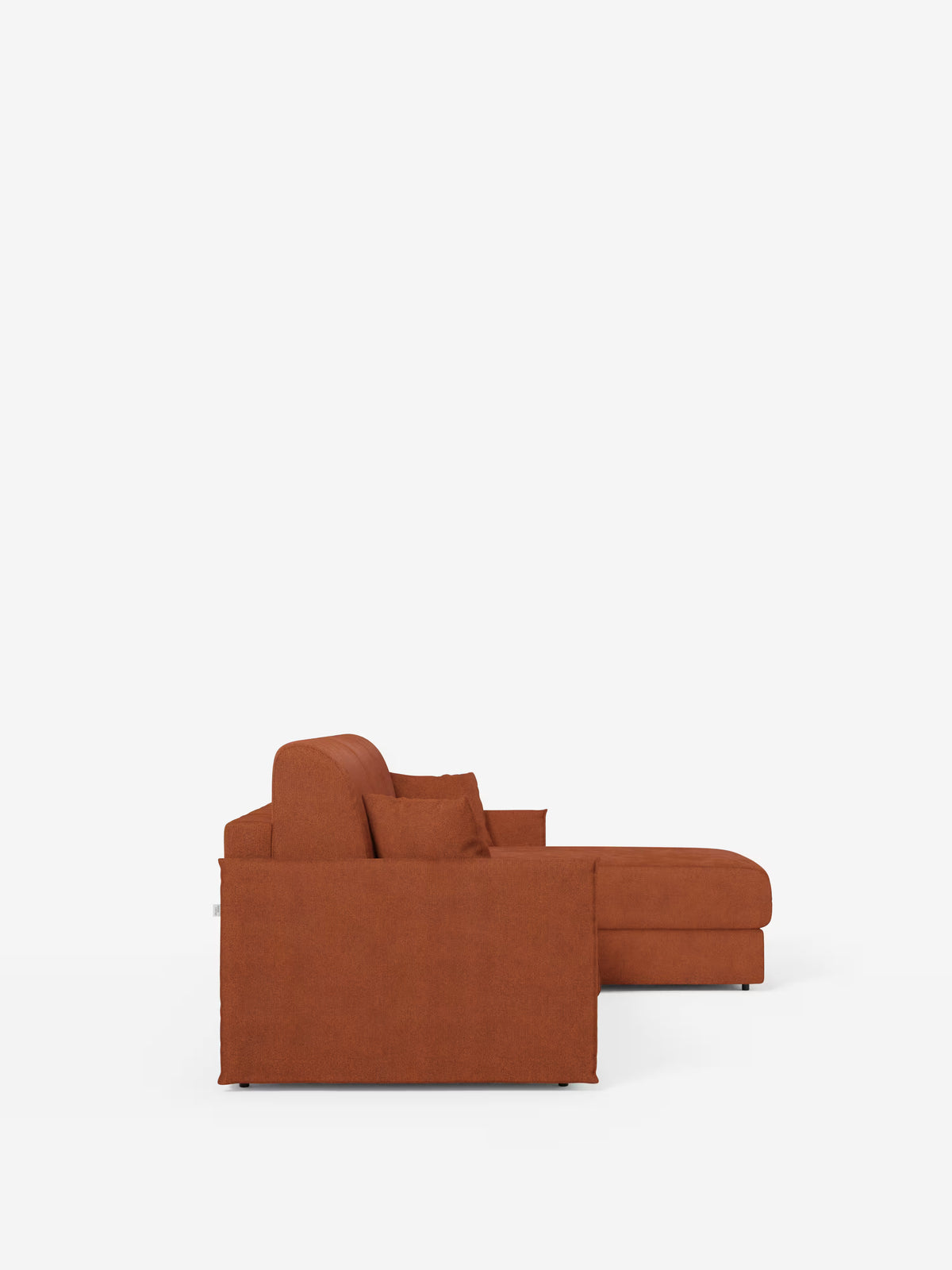 Vista laterale del divano letto angolare con penisola contenitore Evans di Divani.Store, caratterizzato da un design moderno nei toni dell’arancio ruggine con linee pulite, due cuscini di seduta e cuscini dello schienale abbinati, il tutto su uno sfondo bianco a tinta unita. Il lato destro si estende verso l’esterno come una pratica penisola contenitore, garantendo maggiore spazio e funzionalità. La sua silhouette compatta, rivestita in tessuto T23 di facile pulizia, ne esalta lo stile minimalista e