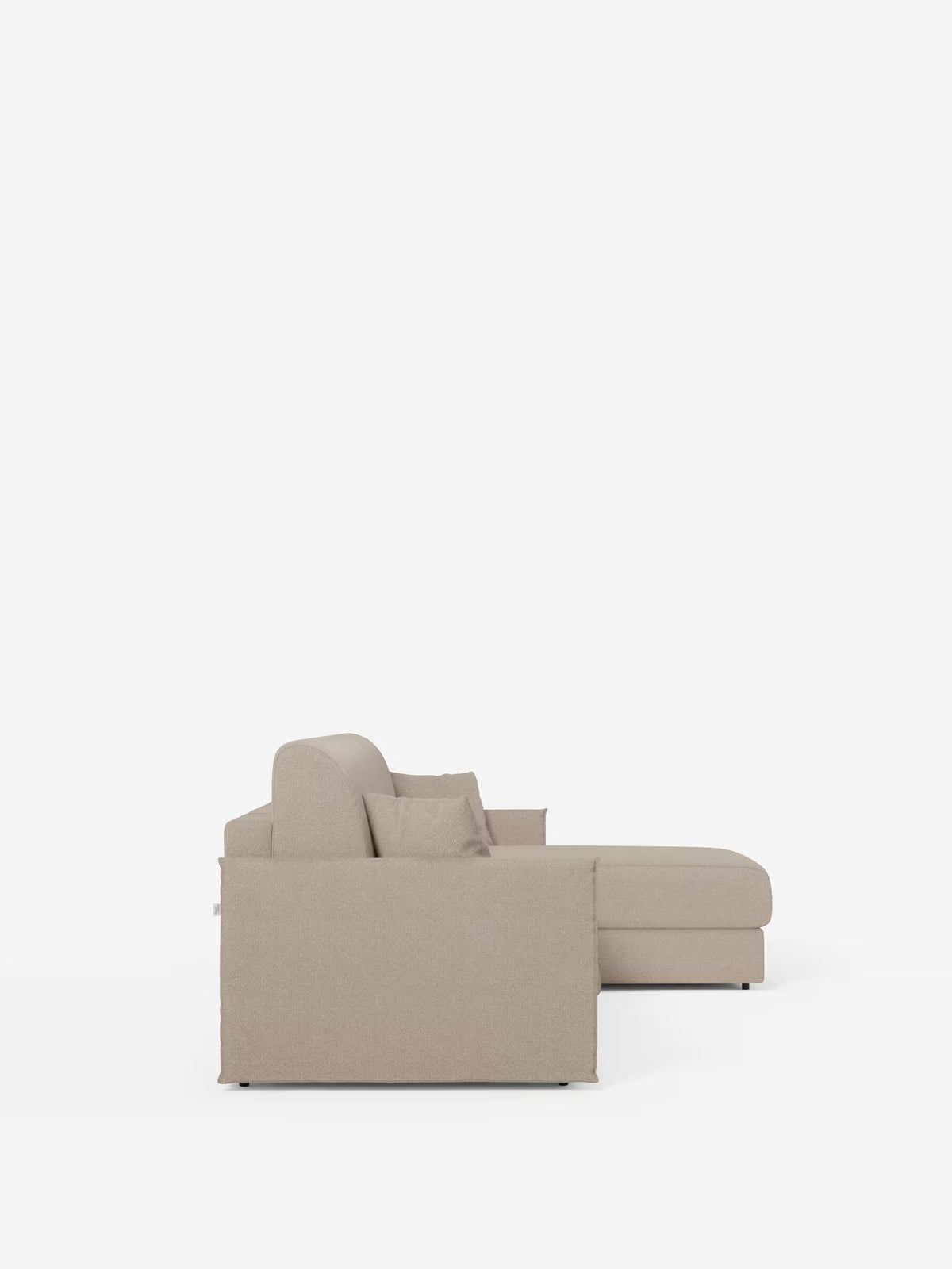 Vista laterale del divano letto angolare con penisola contenitore Evans di Divani.Store, un divano componibile compatto a forma di L di colore beige, rivestito in tessuto T23 antimacchia, dotato di due cuscini di seduta, un cuscino dello schienale e due cuscini decorativi. Il divano presenta un bracciolo spesso sul lato visibile e poggia su gambe sottili, quasi invisibili, che si stagliano su uno sfondo bianco liscio. Questo modello include una pratica penisola contenitore per un maggiore spazio di