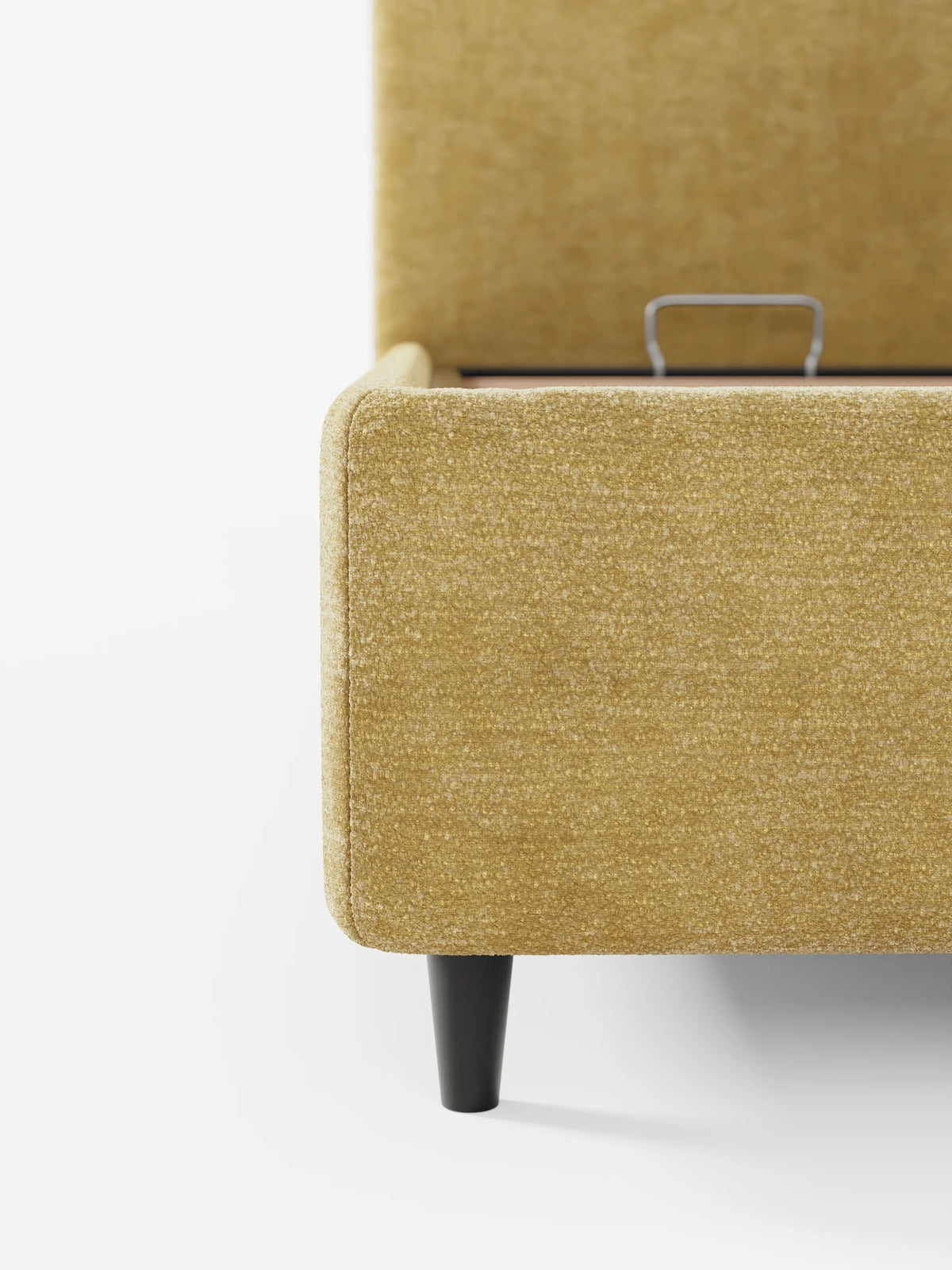 Un letto KAELOS minimal imbottito, color giallo senape, con testiera arrotondata e sottili gambe nere, spicca su uno sfondo bianco liscio; la sua base rivestita in tessuto si solleva per rivelare un vano contenitore.