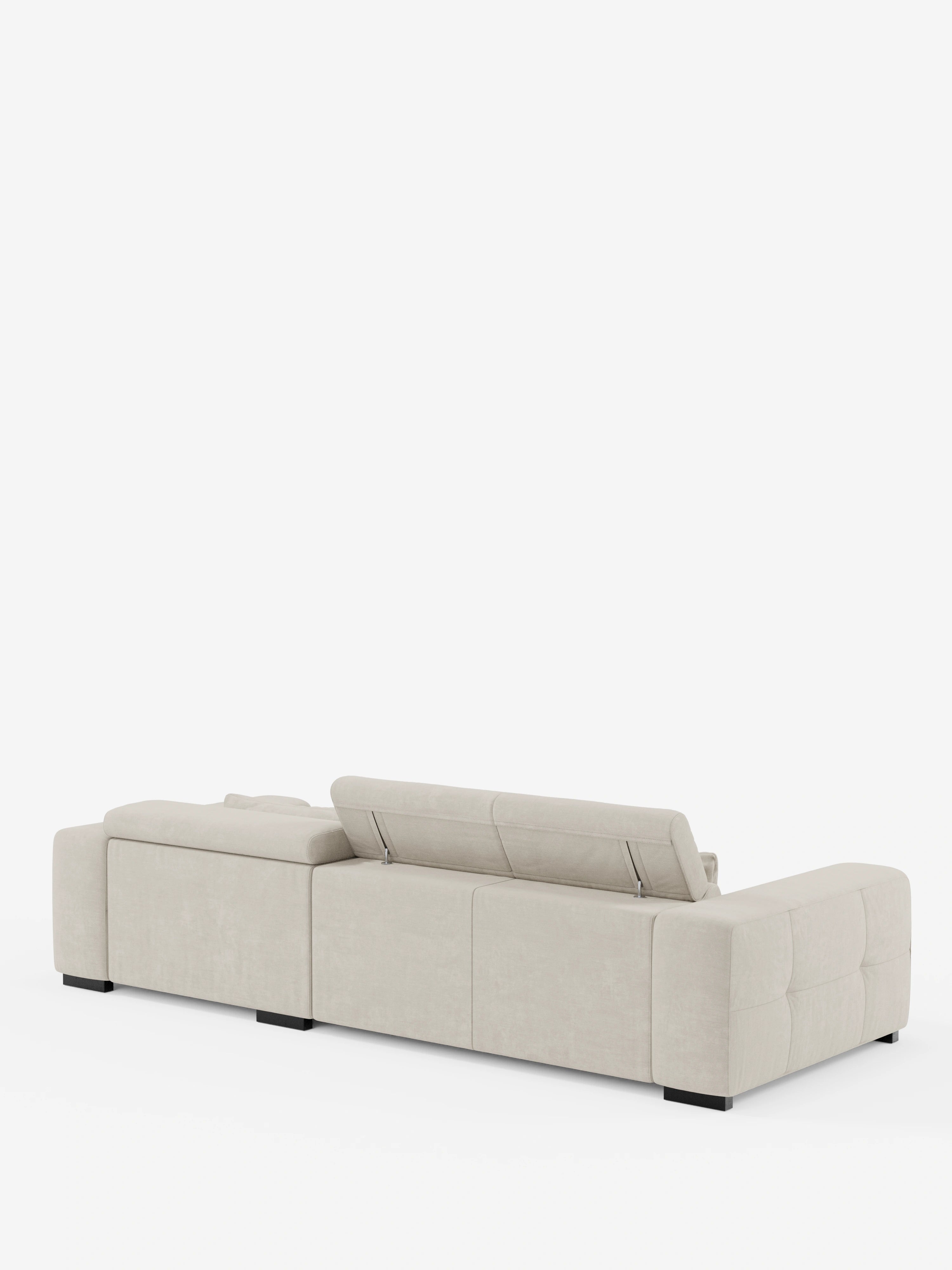 Il moderno divano angolare Monarch in beige chiaro con penisola e sistema Relax Elettrico per l’allungamento delle sedute, firmato Divani.Store, si caratterizza per un profilo basso, ampi braccioli e un poggiatesta parzialmente rialzato e reclinabile. Il divano poggia su gambe corte nere e si stacca su uno sfondo bianco a tinta unita.
