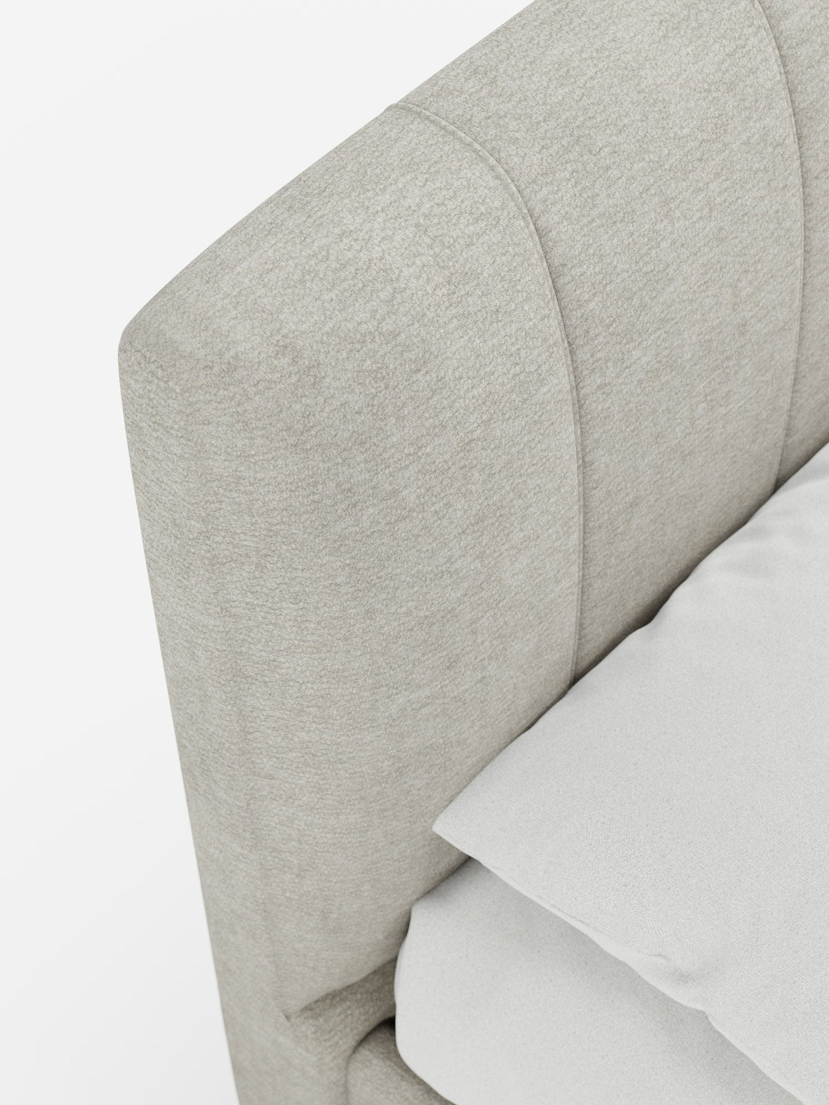 Primo piano del letto imbottito ONYX con contenitore e testiera verticale in tessuto certificato Oeko-Tex® di Letti.store, caratterizzato da una testiera rivestita in tessuto beige chiaro con cuciture curve e verticali. Sul letto, posizionato di traverso su uno sfondo bianco a tinta unita, sono appoggiati un cuscino bianco e una parte di una coperta bianca piegata.