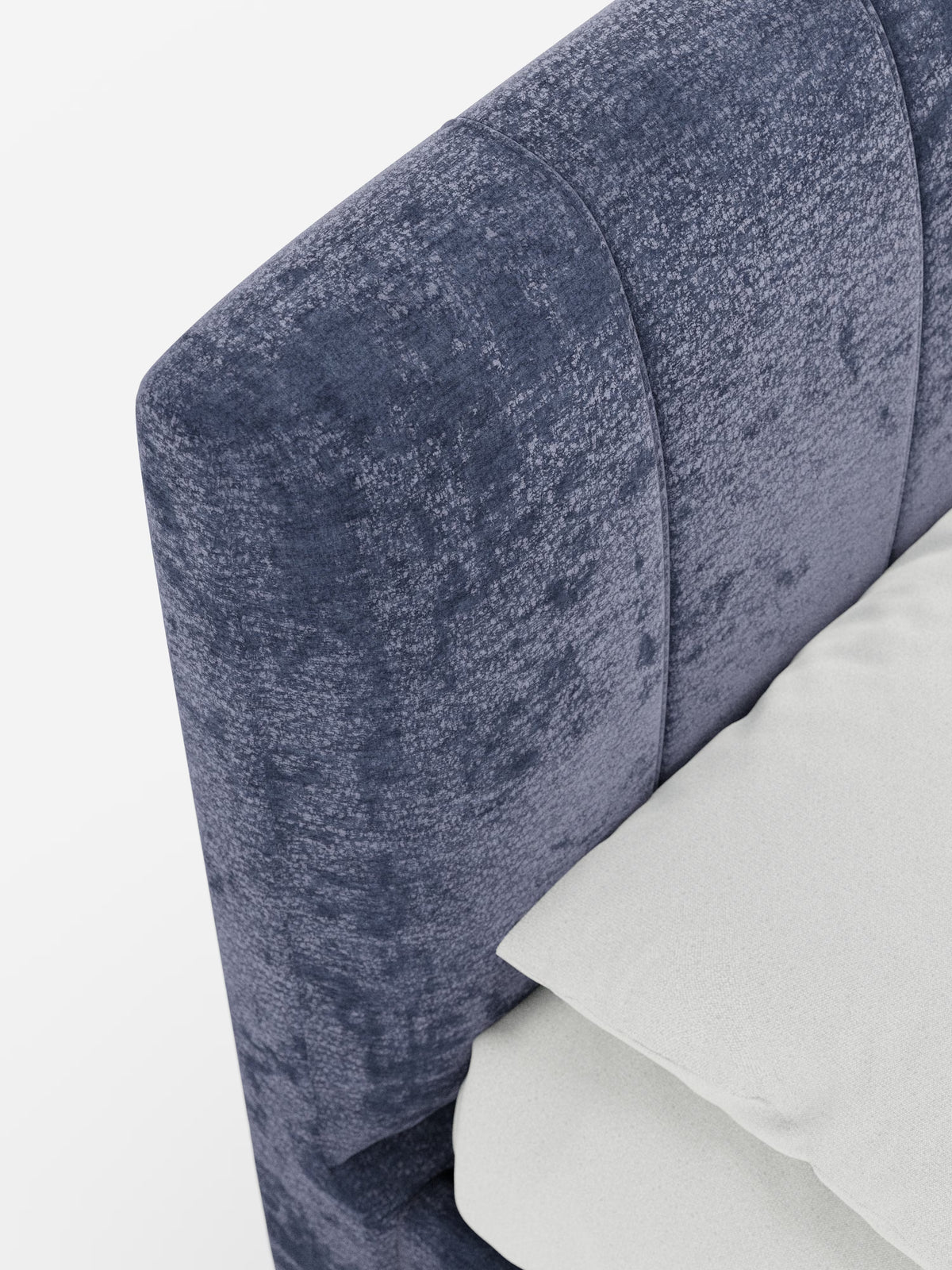 Primo piano del letto imbottito ONYX con contenitore e testiera verticale in tessuto certificato Oeko-Tex® di Letti.store, caratterizzato da una testiera blu scuro con texture e cuciture verticali. Nell’angolo in basso a destra sono visibili un cuscino bianco e una parte di un lenzuolo bianco, che sottolineano il comfort raffinato di questo letto imbottito. Lo sfondo è una superficie bianca, liscia e pulita.
