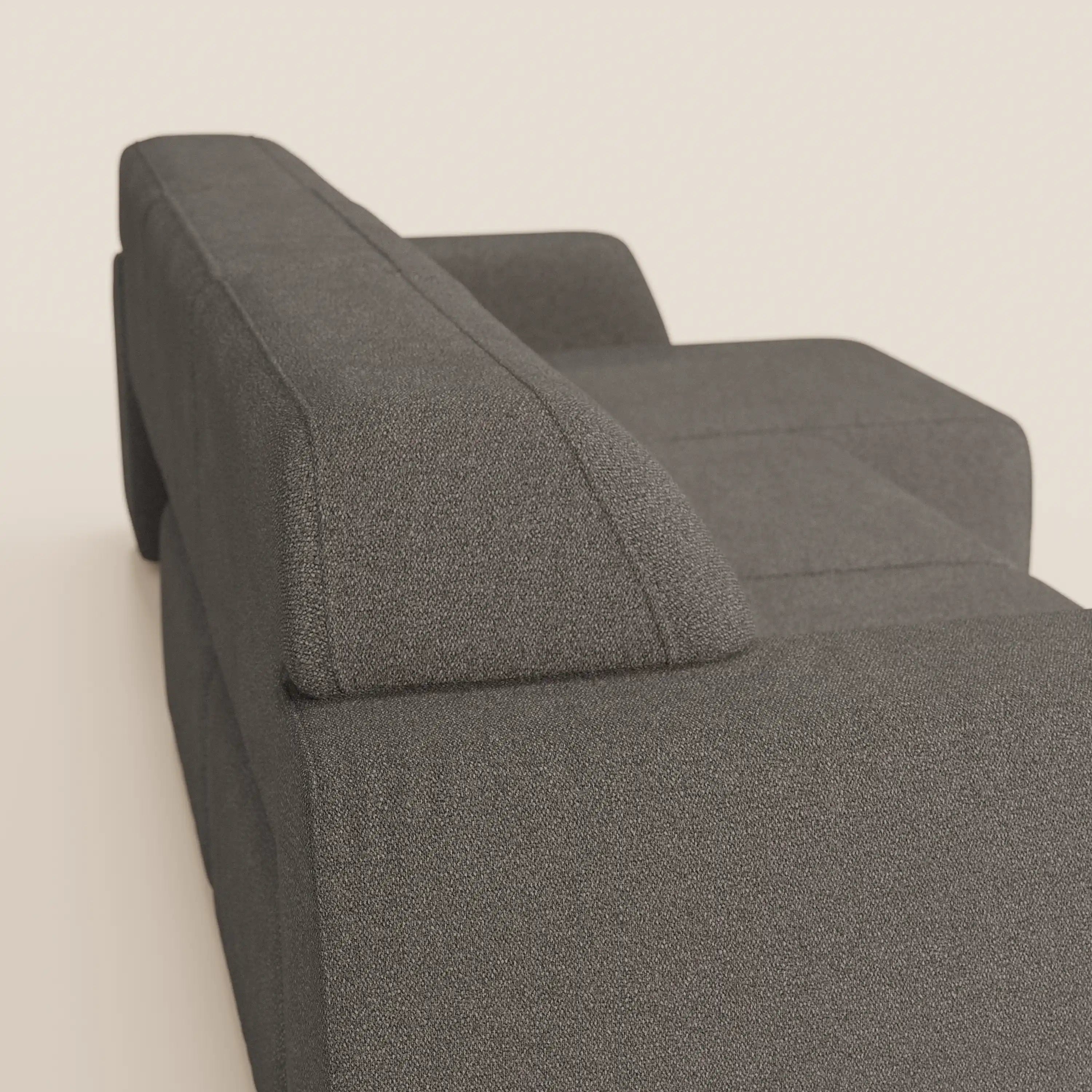 Primo piano del divano Orbit con 3 sedute scorrevoli e allungabili di Divani.Store in grigio scuro, con braccioli e schienale squadrati. Il tessuto effetto cotone smacchiabile T33 spicca su uno sfondo beige chiaro.