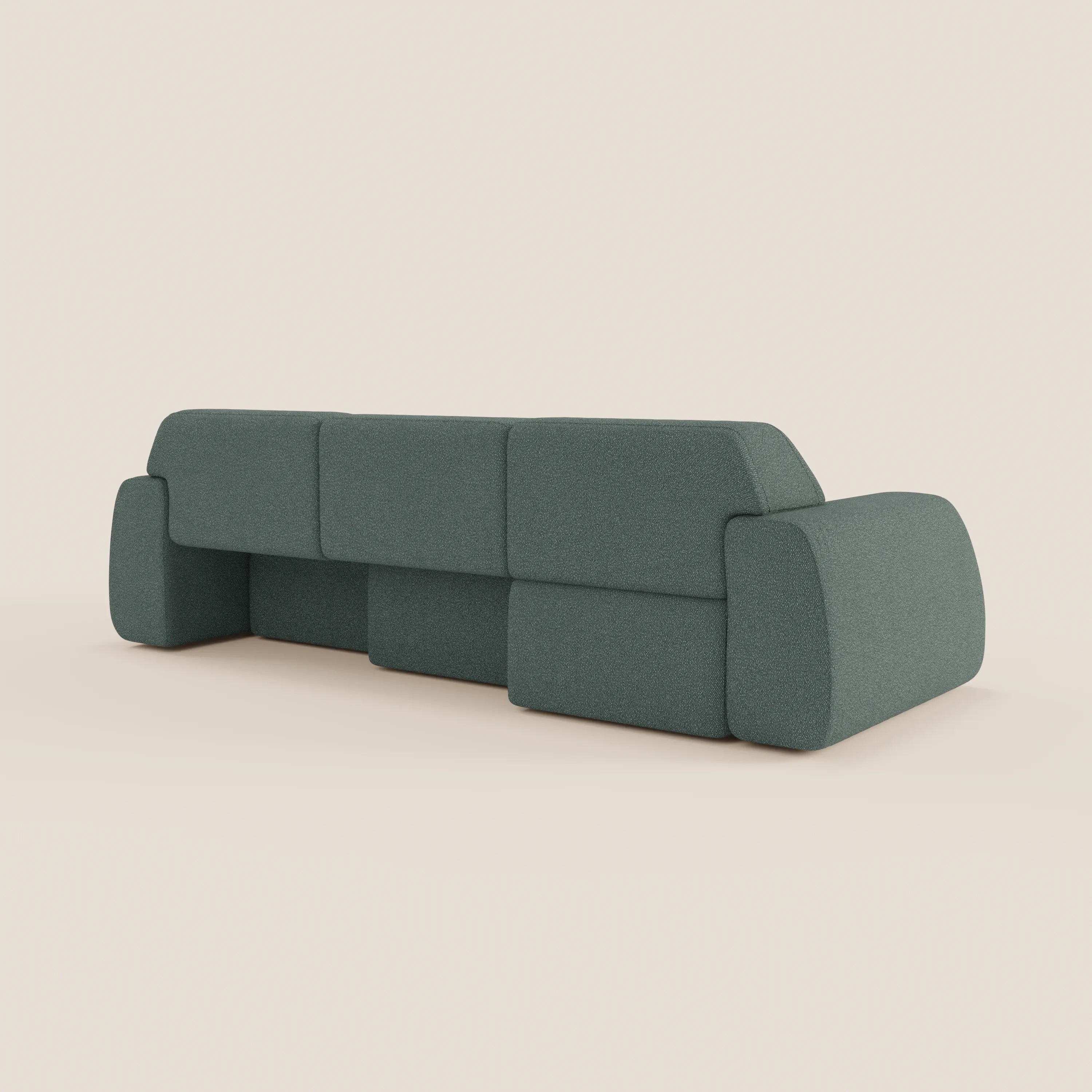 Il Divano Orbit angolare con penisola reversibile di Divani.Store, in tessuto smacchiabile effetto cotone T33 verde-grigio, presenta cuscini geometrici, braccioli larghi e schienale basso, visto da dietro su sfondo beige chiaro.