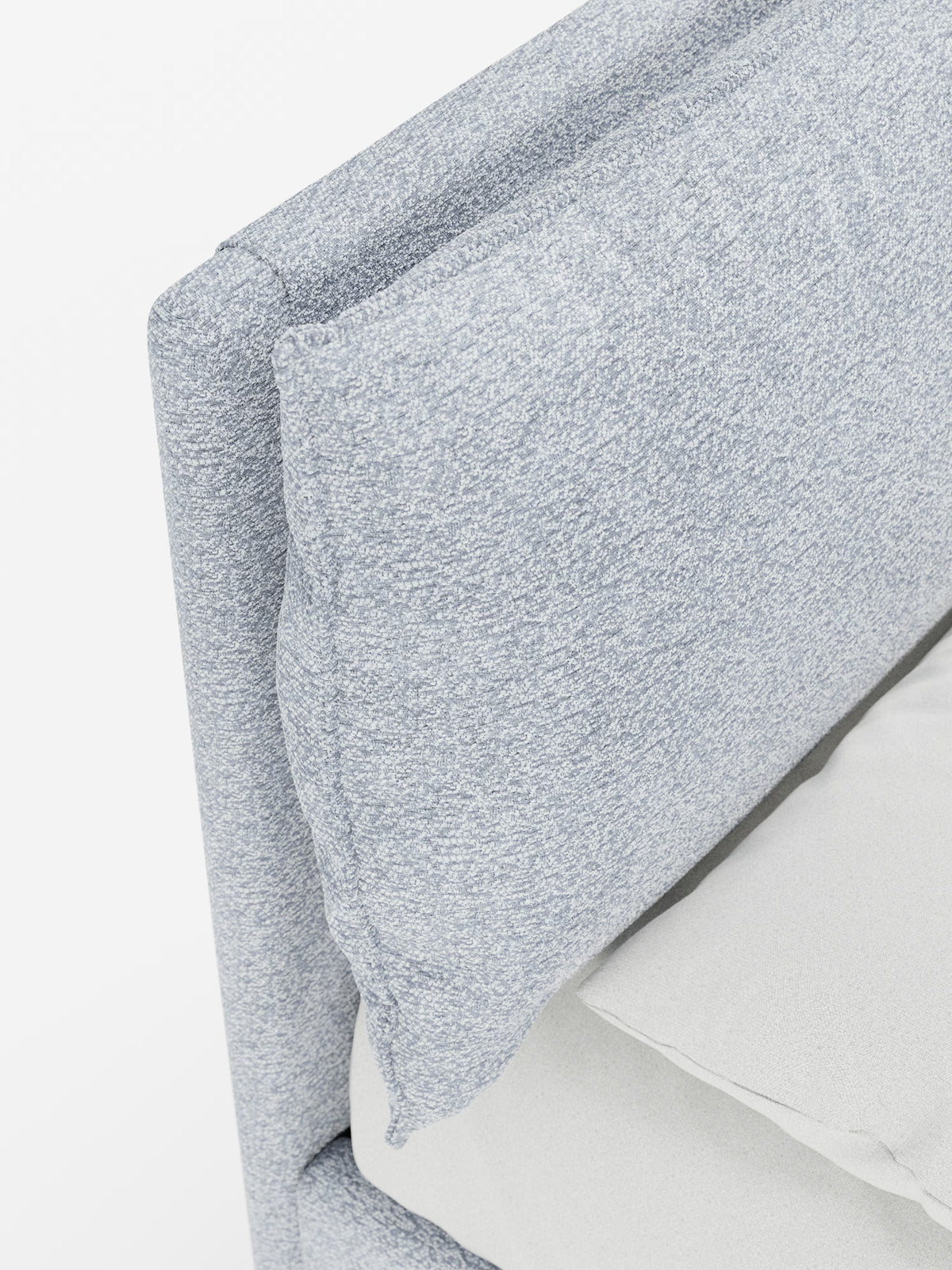 Primo piano del letto imbottito ZAYRON con contenitore e morbidi cuscini regolabili di Letti.store, che mette in risalto la testiera in tessuto grigio chiaro con trama in rilievo, certificata Oeko-Tex®, dotata di un morbido cuscino regolabile. Nell’angolo in basso a destra si intravede una parte di un lenzuolo bianco o color crema su uno sfondo bianco a tinta unita.