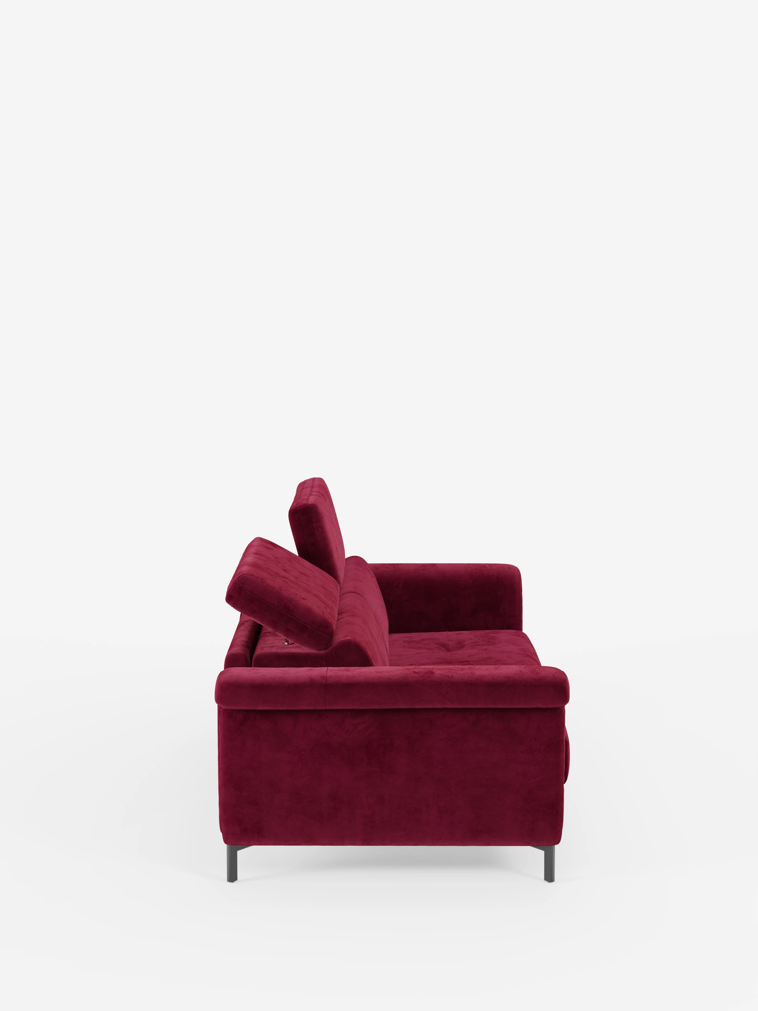 Una vista laterale del divano letto di design Capri di Divani.Store, presentato in un rosso intenso, caratterizzato da gambe alte nere e manifattura italiana. Questo divano moderno vanta un'imbottitura spessa, braccioli bassi e poggiatesta reclinabili regolabili, il tutto rivestito in un lussuoso tessuto effetto velluto smacchiabile T30, resistente alle macchie, che risalta su uno sfondo bianco a tinta unita.
