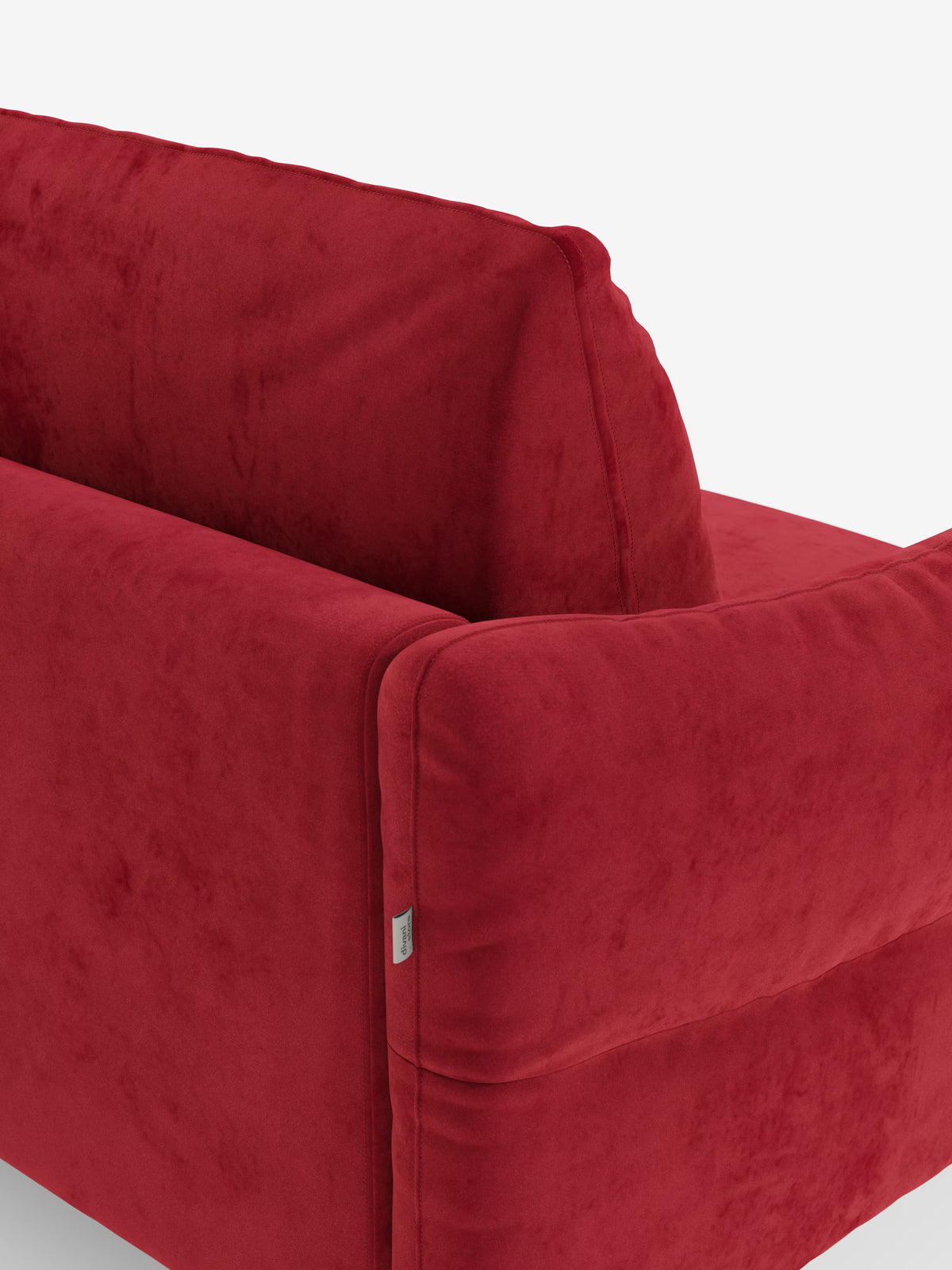 Un primo piano del divano letto Dalia a 2, 3 e 4 posti con materasso H18 di Divani.Store, rivestito in moderno tessuto vellutino T30 antimacchia in una ricca tonalità di rosso intenso. L’immagine mette in risalto i braccioli e lo schienale del divano, evidenziandone la consistenza morbida e vellutata e le cuciture pulite e minimaliste. Sul lato, su uno sfondo bianco, è visibile una piccola etichetta in tessuto.