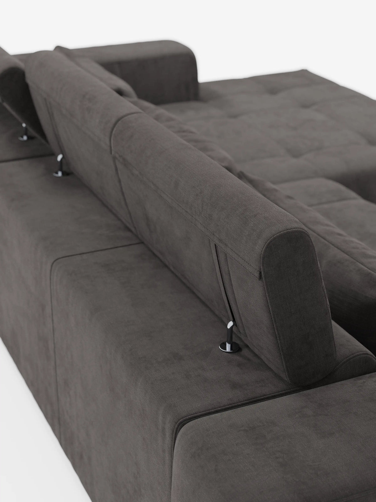Il divano angolare Monarch con penisola e funzione relax elettrica per l’allungamento delle sedute di Divani.Store è presentato in tessuto T31 grigio scuro, morbido e resistente alle macchie. I poggiatesta regolabili del divano sono posizionati in posizione verticale, mettendo in risalto le sue linee pulite e moderne e i cuscini trapuntati in un sobrio stile capitonné. Fotografato da un’angolazione posteriore su sfondo bianco, il design contemporaneo del divano modulare è chiaramente visibile.