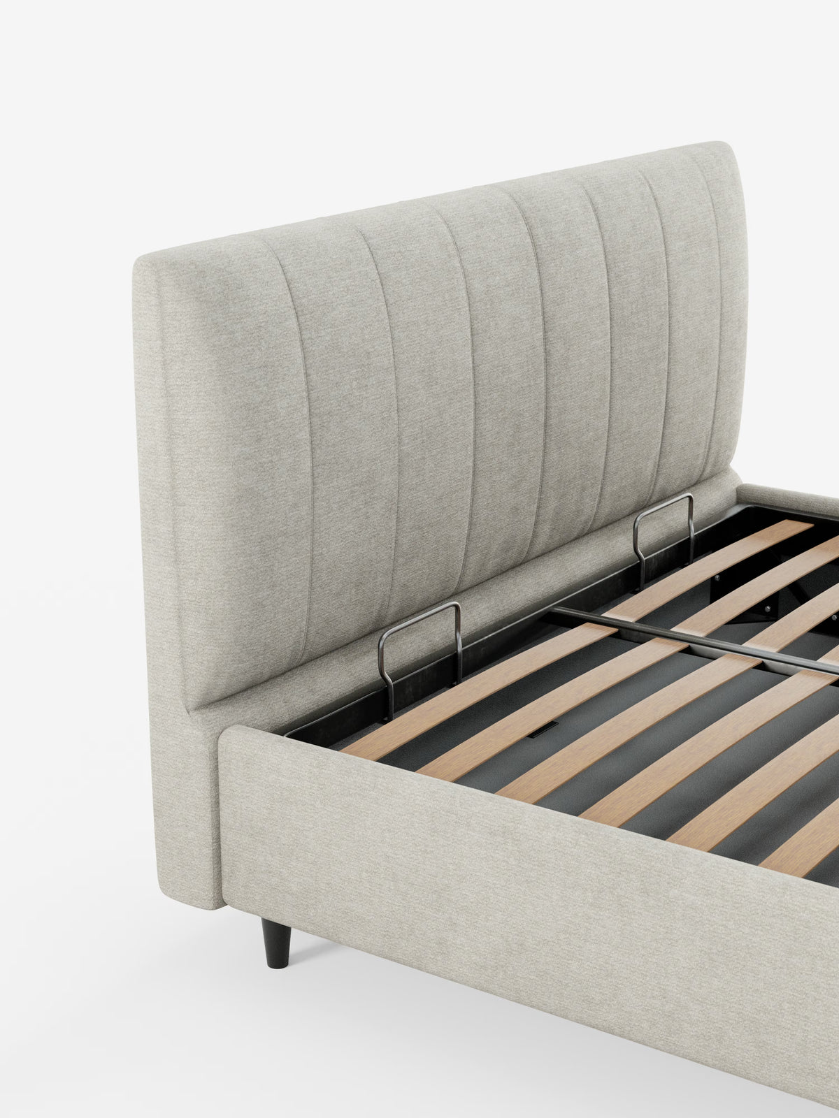 Il letto imbottito ONYX con contenitore e testiera verticale in tessuto certificato Oeko-Tex® di Letti.store presenta una struttura imbottita color beige con una testiera alta e scanalata verticalmente. In assenza del materasso, sono visibili le doghe in legno e i supporti in metallo. Questo elegante letto poggia su corte gambe nere ed è ritratto su uno sfondo bianco a tinta unita.