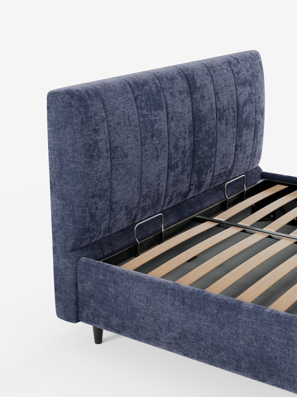 Un primo piano del letto imbottito ONYX con contenitore e testiera verticale in tessuto certificato Oeko-Tex® di Letti.store, che mette in risalto la sua testiera alta e morbida in blu navy con cuciture verticali. La struttura presenta doghe in legno a vista sostenute da elementi in metallo nero e gambe corte nere, il tutto su uno sfondo bianco a tinta unita.