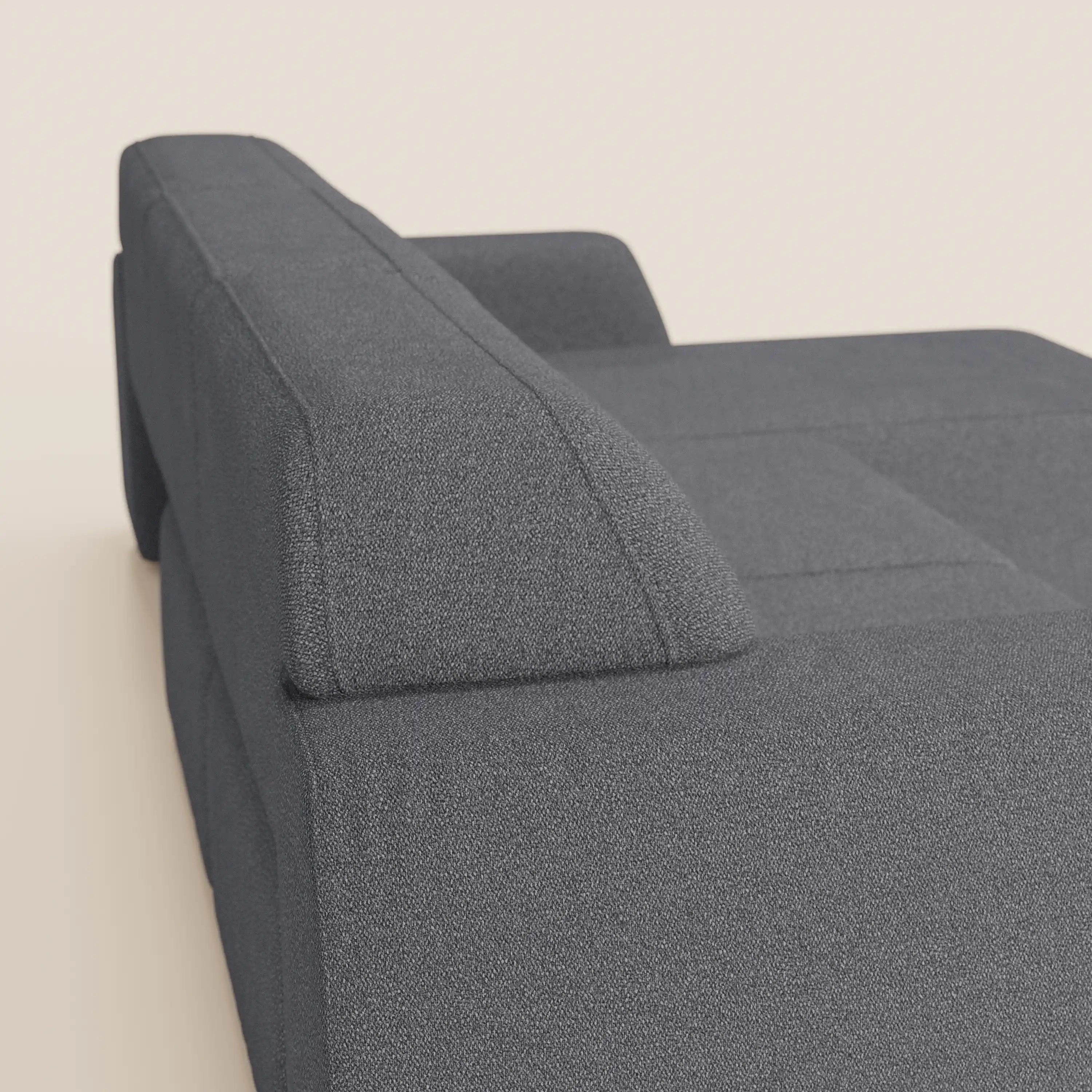 Un primo piano di Orbit Divano angolare con penisola reversibile di Divani.Store mostra il rivestimento in cotone effetto T33, le linee eleganti e il bracciolo squadrato, ripreso dall'angolo posteriore su uno sfondo beige chiaro.