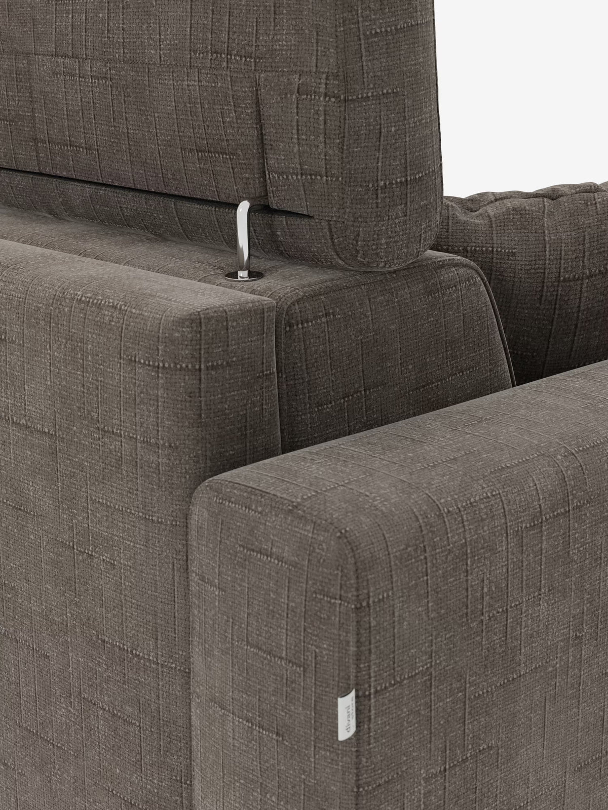 Primo piano del divano letto matrimoniale Pegaso di Divani.Store, realizzato in moderno tessuto jacquard T22 marrone, resistente alle macchie e con motivo a quadrati. Il poggiatesta regolabile è sostenuto da un’elegante asta metallica, mentre sul bracciolo è cucita una piccola etichetta in tessuto bianco. Uno sfondo luminoso, prevalentemente bianco, mette in risalto la raffinata trama del divano.