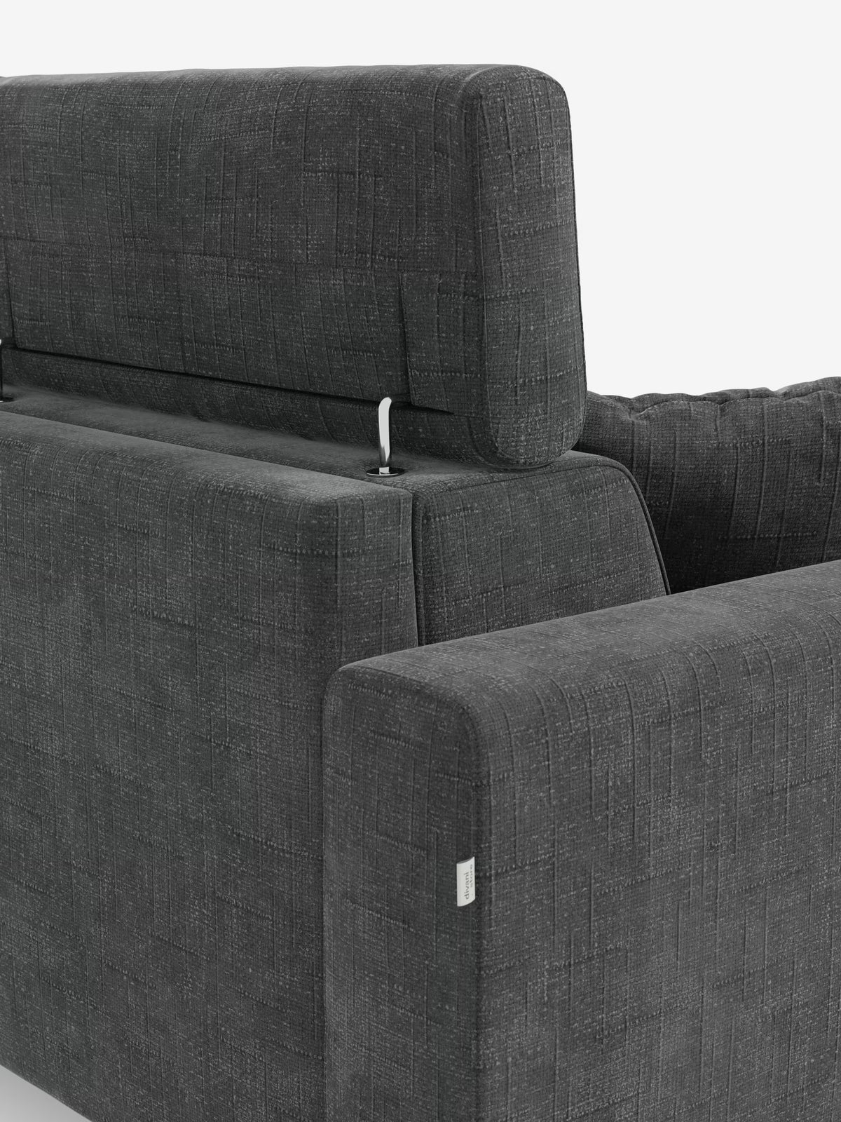 Un primo piano del divano letto angolare Pegaso con poggiatesta reclinabili e penisola contenitore in tessuto jacquard smacchiabile T22 di Divani.Store mette in risalto lo schienale e i braccioli del divano, realizzati in tessuto grigio scuro dalla trama rigata. Lo schienale è dotato di un supporto metallico regolabile per il poggiatesta, mentre sul bracciolo è visibile una piccola etichetta in tessuto, il tutto su uno sfondo bianco a tinta unita. Questo complemento d’arredo moderno coniuga stile e