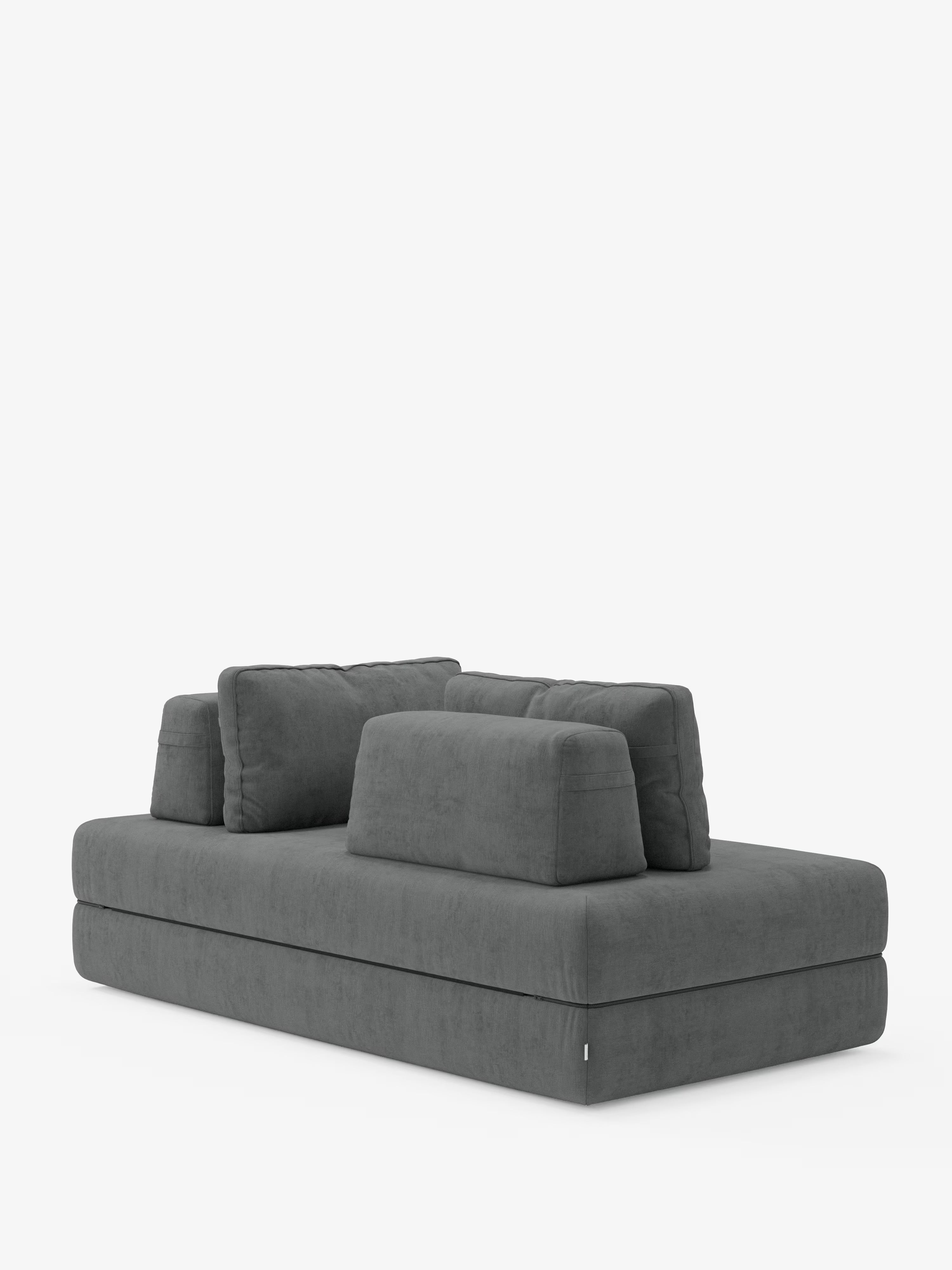 Un divano letto matrimoniale Rift in grigio contemporaneo, disponibile nelle versioni a 2 e 3 posti, firmato Divani.Store, è esposto su uno sfondo bianco. Questo divano di design presenta un profilo ribassato con spessi cuscini rettangolari che formano la seduta e lo schienale, completati da cuscini schienali più piccoli e rimovibili per un maggiore comfort. Il look complessivo è minimalista e geometrico, con un rivestimento in tessuto T31 resistente alle macchie e un materasso in memory foam alto 24 cm.