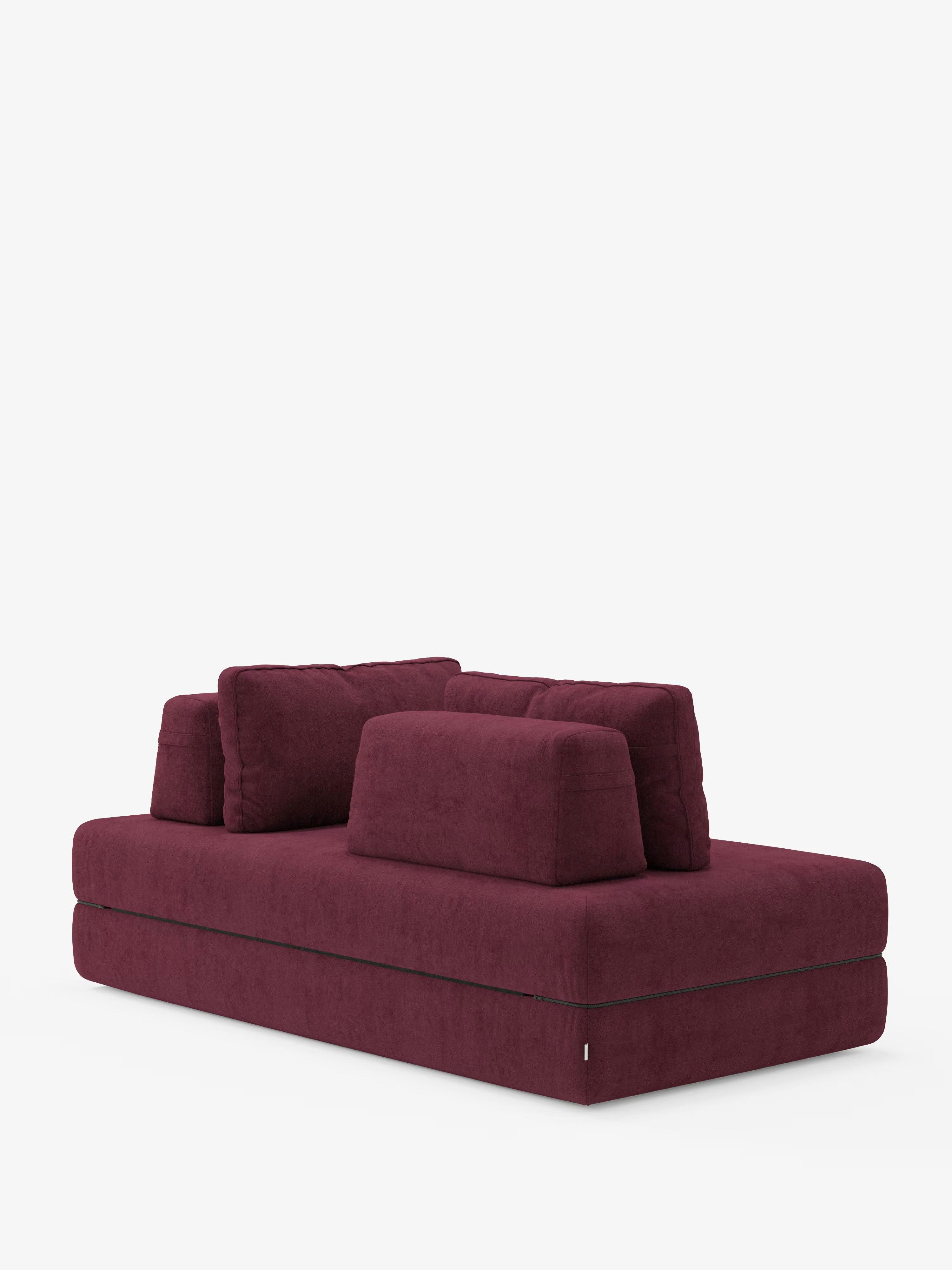 Un moderno divano letto matrimoniale Rift di Divani.Store, in un intenso bordeaux, caratterizzato da spessi cuscini di seduta e tre morbidi cuscini dello schienale rimovibili, è esposto su uno sfondo bianco a tinta unita. Il suo design squadrato e dal profilo ribassato, insieme al materasso in memory foam alto 24 cm rivestito in tessuto T31 antimacchia, lo rendono il complemento d’arredo contemporaneo perfetto per qualsiasi zona giorno.