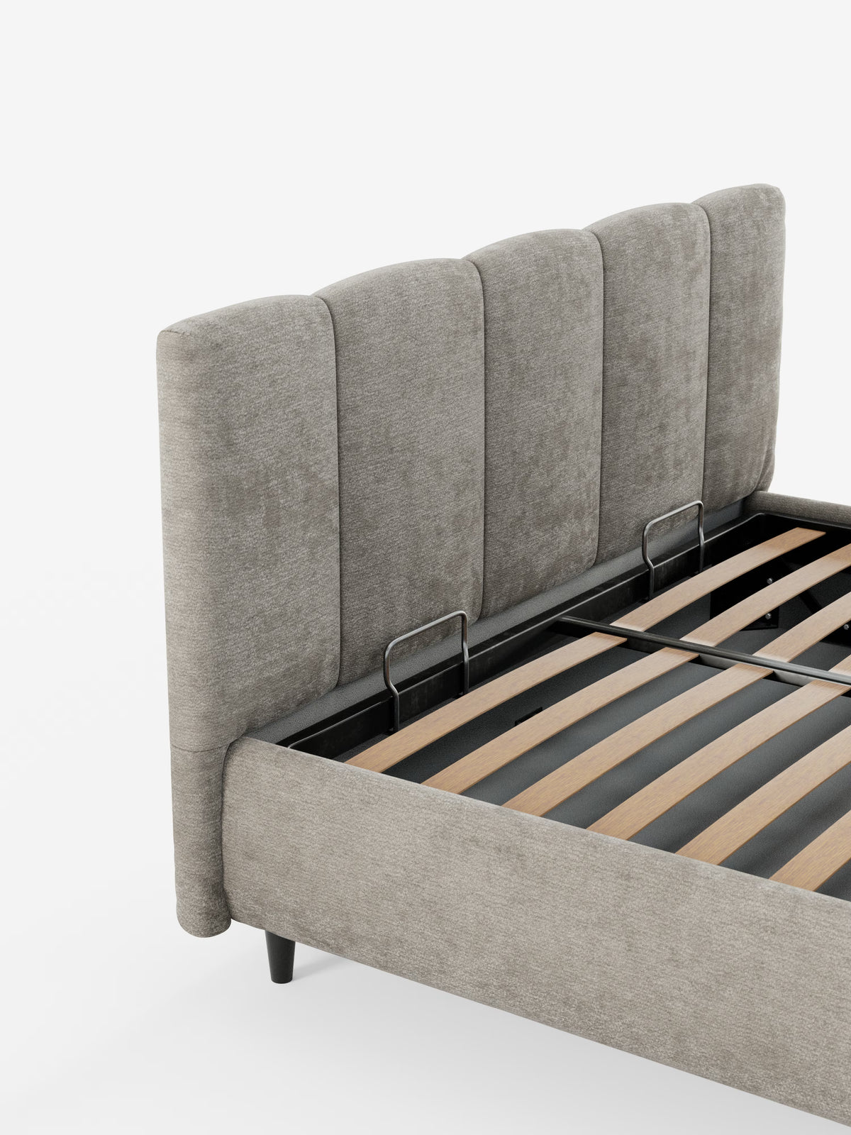 Un primo piano del letto imbottito ARKAM di Letti.store con contenitore e testiera a lavorazione verticale, caratterizzato da un’alta testiera grigia imbottita con pannelli verticali, rivestita in tessuto certificato Oeko-Tex® e dal design shabby chic. Sono visibili le doghe in legno e la struttura in metallo nero del letto, insieme a due staffe argentate. Lo sfondo è bianco.