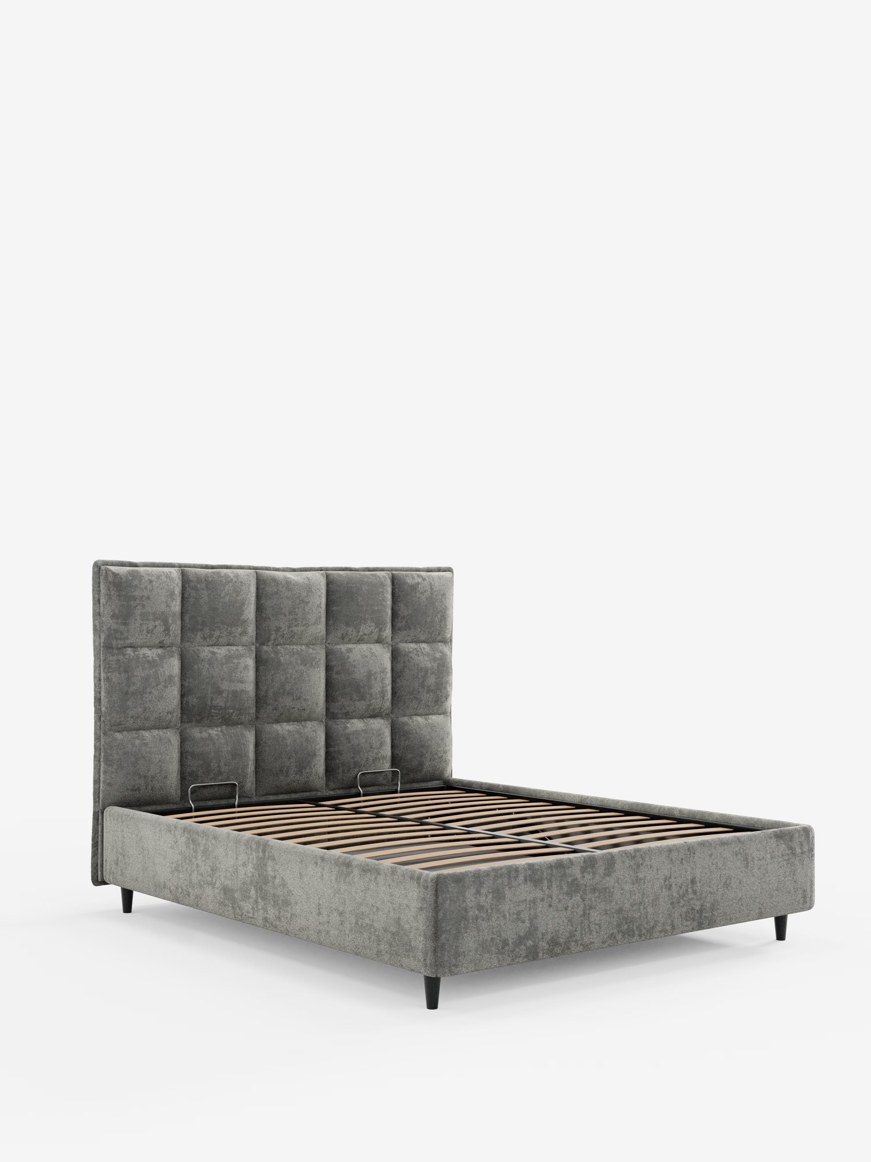 Un moderno letto imbottito AURO con contenitore e testiera capitonné alta in ciniglia Oeko-Tex® di Letti.store, caratterizzato da una testiera alta e capitonné e da doghe in legno, il tutto rivestito in un elegante tessuto grigio. La struttura del letto è inquadrata su uno sfondo bianco a tinta unita, lasciato vuoto per mettere in risalto la sua struttura e i materiali di alta qualità.