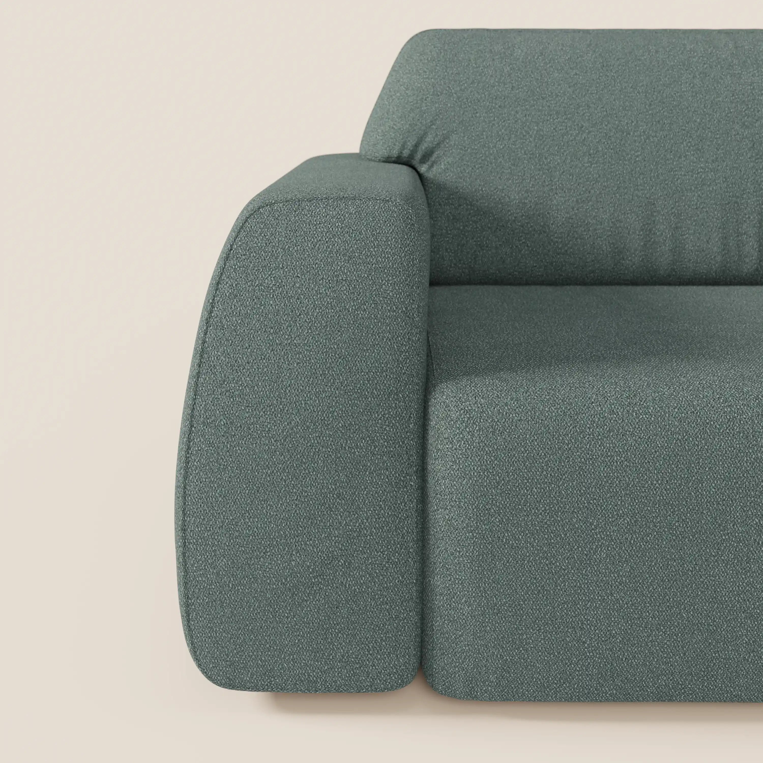 Primo piano del divano Orbit con 3 sedute scorrevoli e allungabili in tessuto effetto cotone smacchiabile T33 di Divani.Store, con bordi arrotondati, rivestimento sfoderabile dalla texture morbida e design minimalista in verde tenue su sfondo beige chiaro.