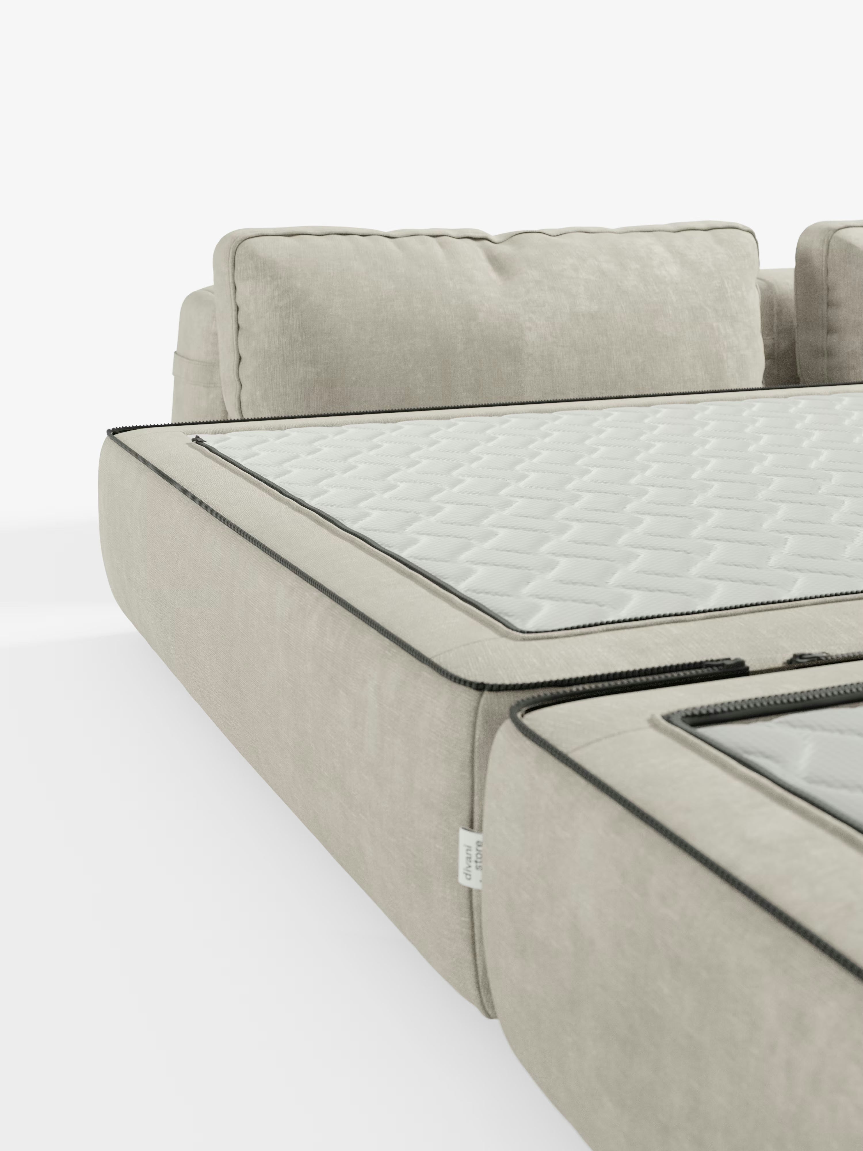 Primo piano di un divano letto matrimoniale Rift color beige chiaro a 2 e 3 posti di Divani.Store, caratterizzato da schienali orientabili e cuscini di seduta rimovibili che rivelano al loro interno un materasso in memory foam bianco trapuntato (alto 24 cm), delimitato da cerniere nere a vista. Il tutto su uno sfondo semplice e minimalista per mettere in risalto il tessuto T31 dal tocco piacevole al tatto e il design modulare del divano.