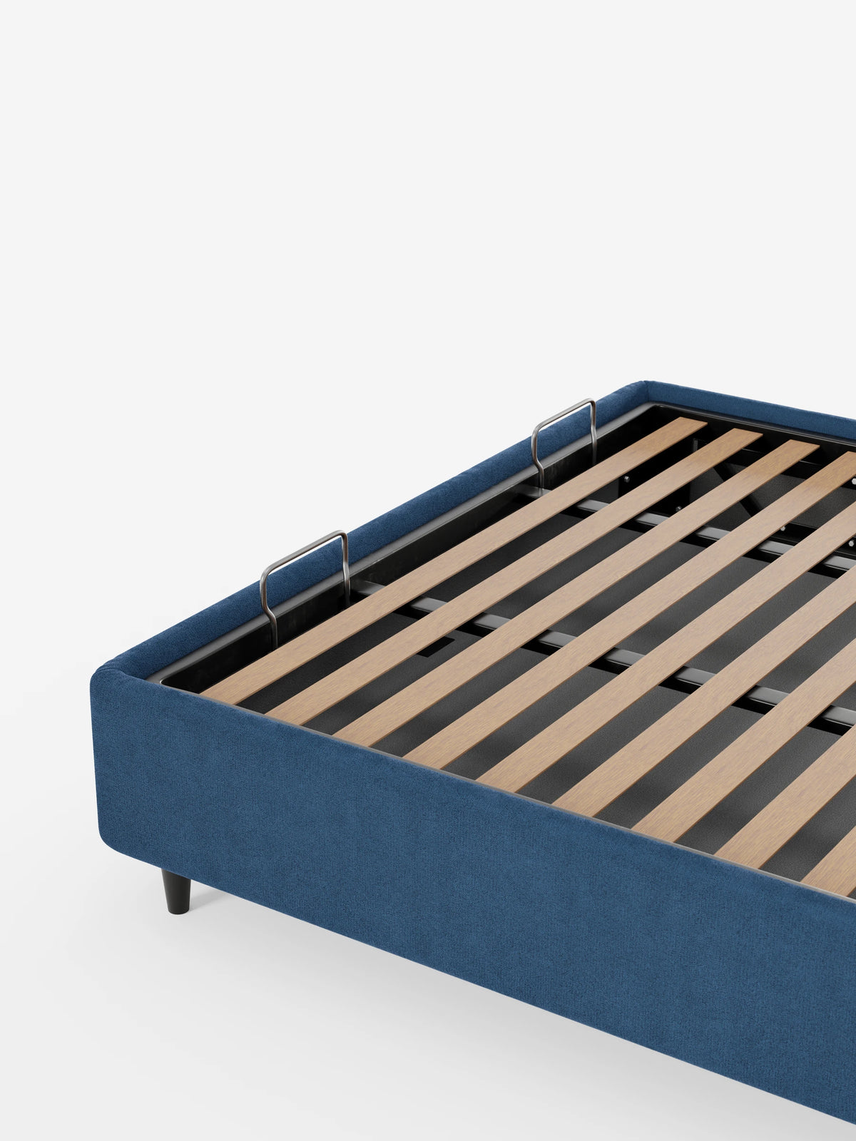 Vista dall'alto di un letto sommier imbottito ERON blu con contenitore, rivestito in tessuto impermeabile certificato Oeko-Tex, dotato di una base a doghe in legno, due fermi metallici per il materasso e piedini corti di colore scuro su sfondo bianco.