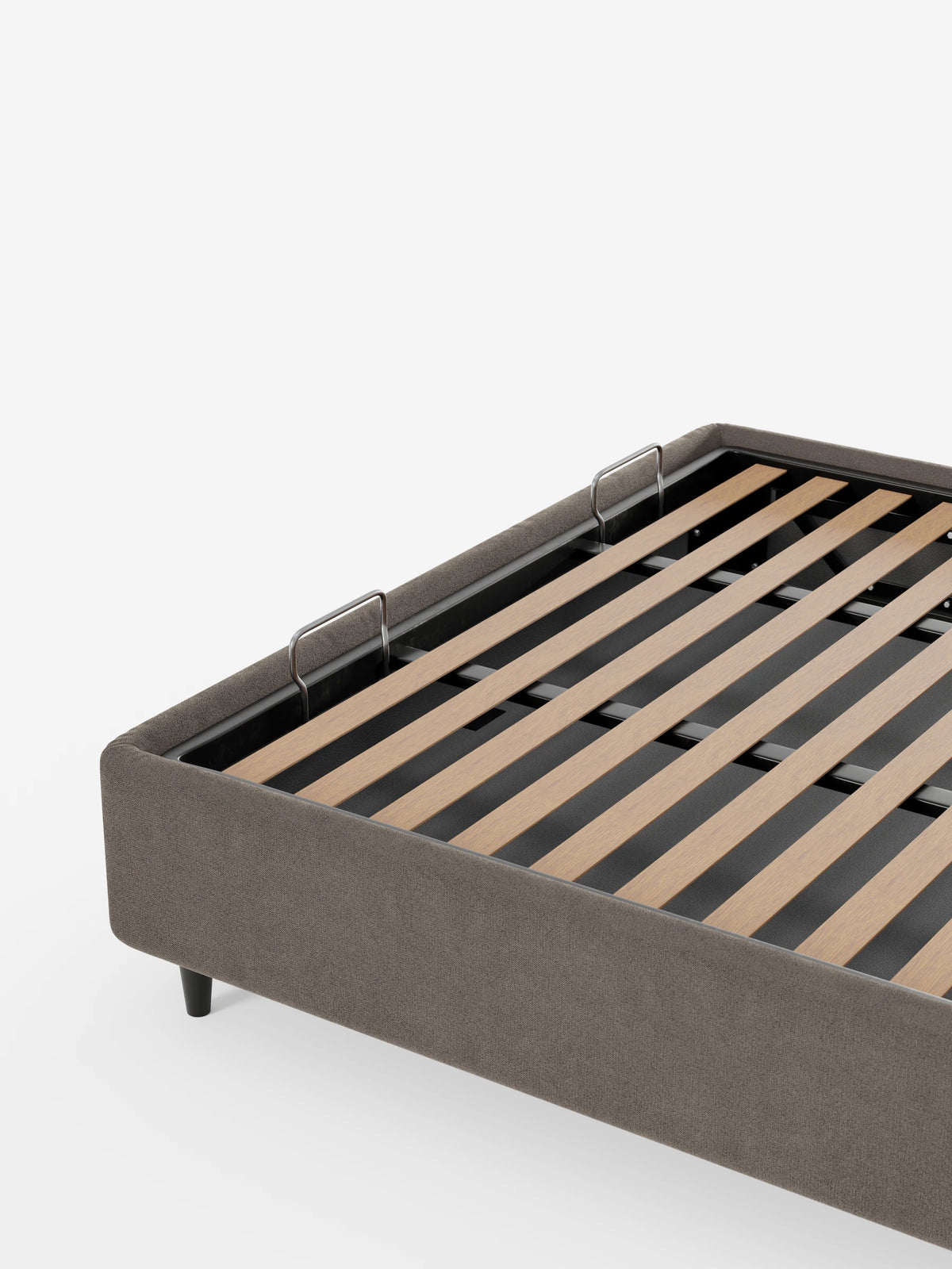 Una vista di profilo del letto sommier imbottito ERON con vano contenitore in tessuto impermeabile certificato Oeko-Tex color taupe, caratterizzato da doghe in legno chiaro e due fermi metallici per il materasso su uno sfondo bianco a tinta unita.