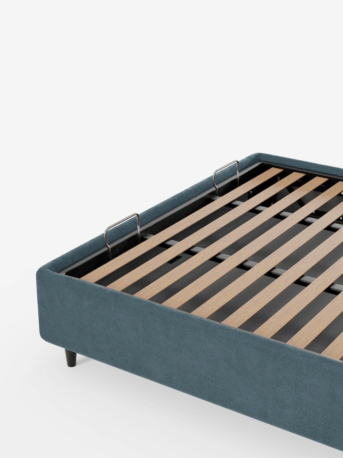 Il letto sommier imbottito ERON con contenitore, realizzato in tessuto impermeabile certificato Oeko-Tex in blu tenue, è raffigurato con la base del materasso sollevata per mostrare le doghe in legno, due maniglie in metallo e le gambe cilindriche scure su uno sfondo bianco.
