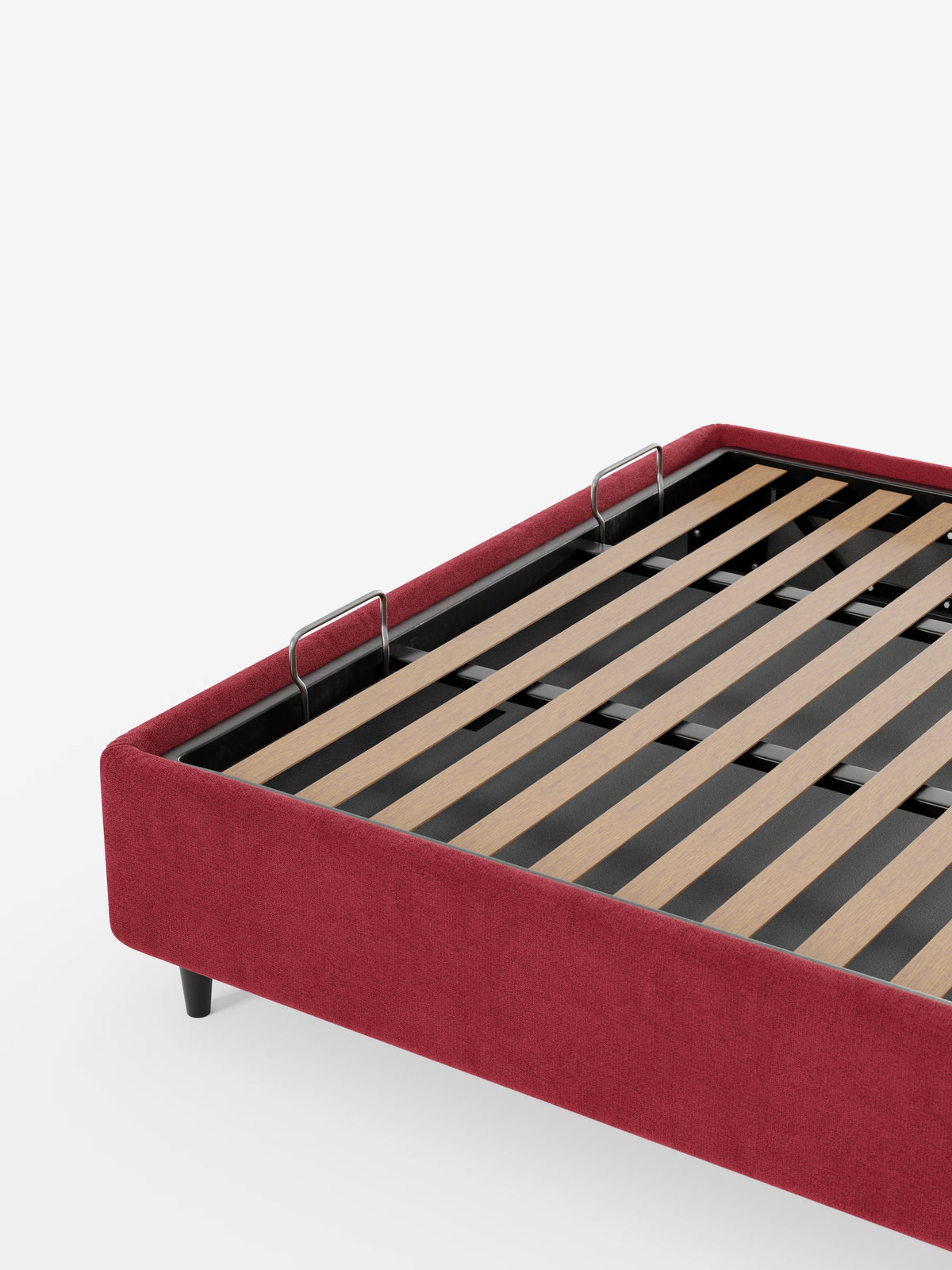 Il letto sommier imbottito ERON con vano contenitore in tessuto impermeabile certificato Oeko-Tex color rosso intenso, dotato di base a doghe in legno, telaio rettangolare, gambe corte scure e due fermi metallici a forma di U per il materasso.