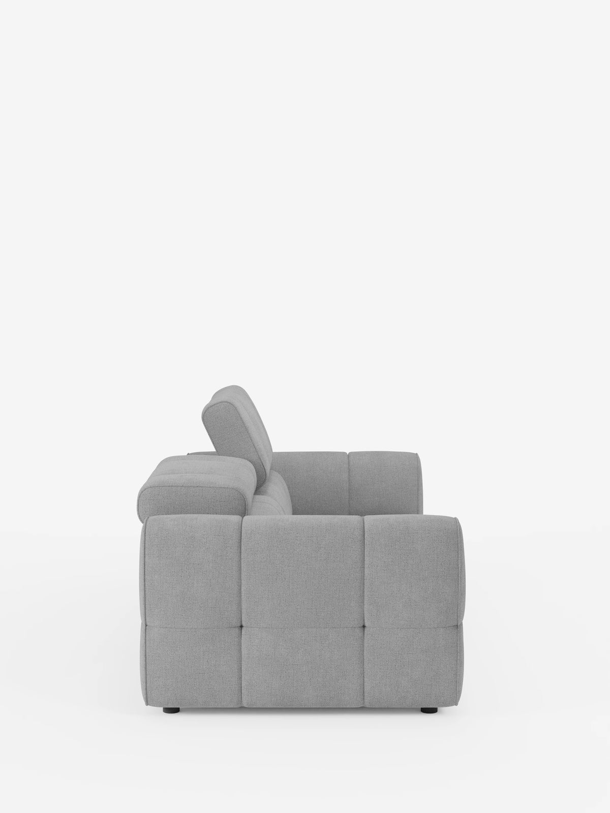 Vista di profilo di un divano modulare Giotto a 3 posti color grigio chiaro, con poggiatesta reclinabili e funzione relax elettrica opzionale, rivestito in tessuto smacchiabile T23, caratterizzato da una struttura squadrata con trapuntatura, braccioli bassi e un poggiatesta reclinabile in posizione verticale su fondo bianco.