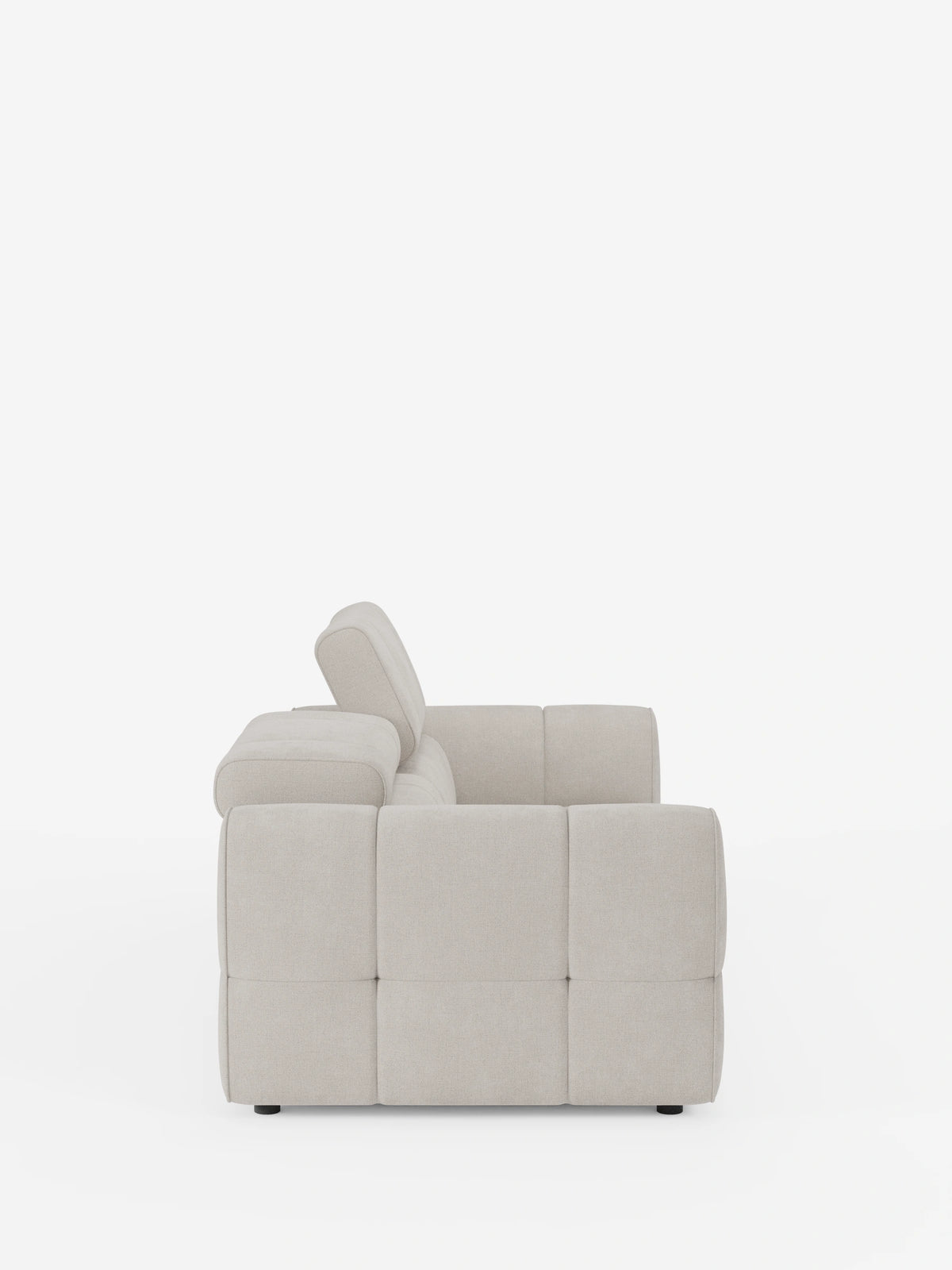 Vista laterale di un divano modulare Giotto a 3 posti color beige chiaro, con poggiatesta reclinabili e funzione relax elettrica opzionale, rivestito in tessuto smacchiabile T23, caratterizzato da tessuto trapuntato a quadrati, ampi braccioli e poggiatesta rialzato su sfondo bianco.